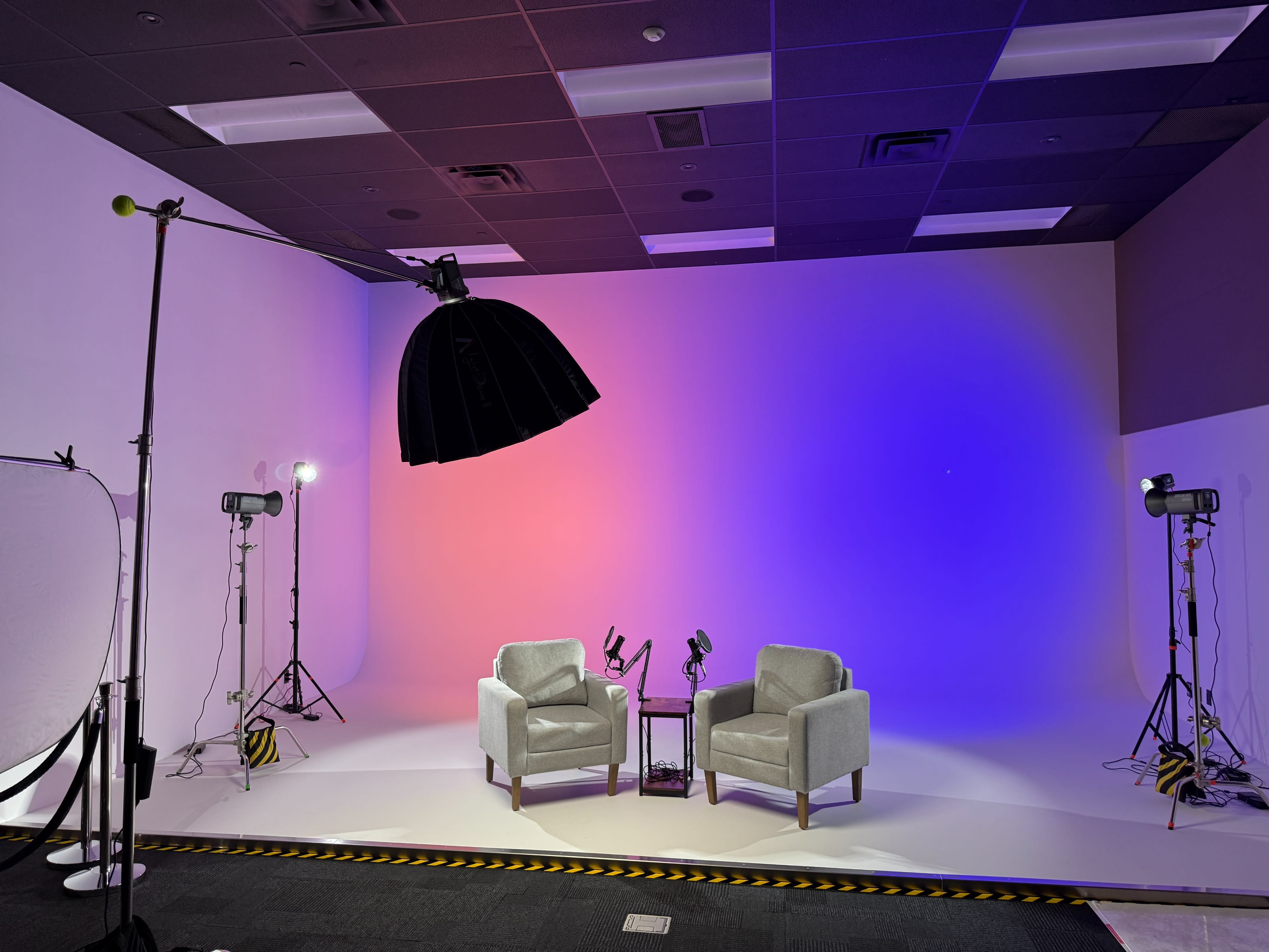 A photographer captures a group of models posing in a well-lit studio for a fashion photoshoot.