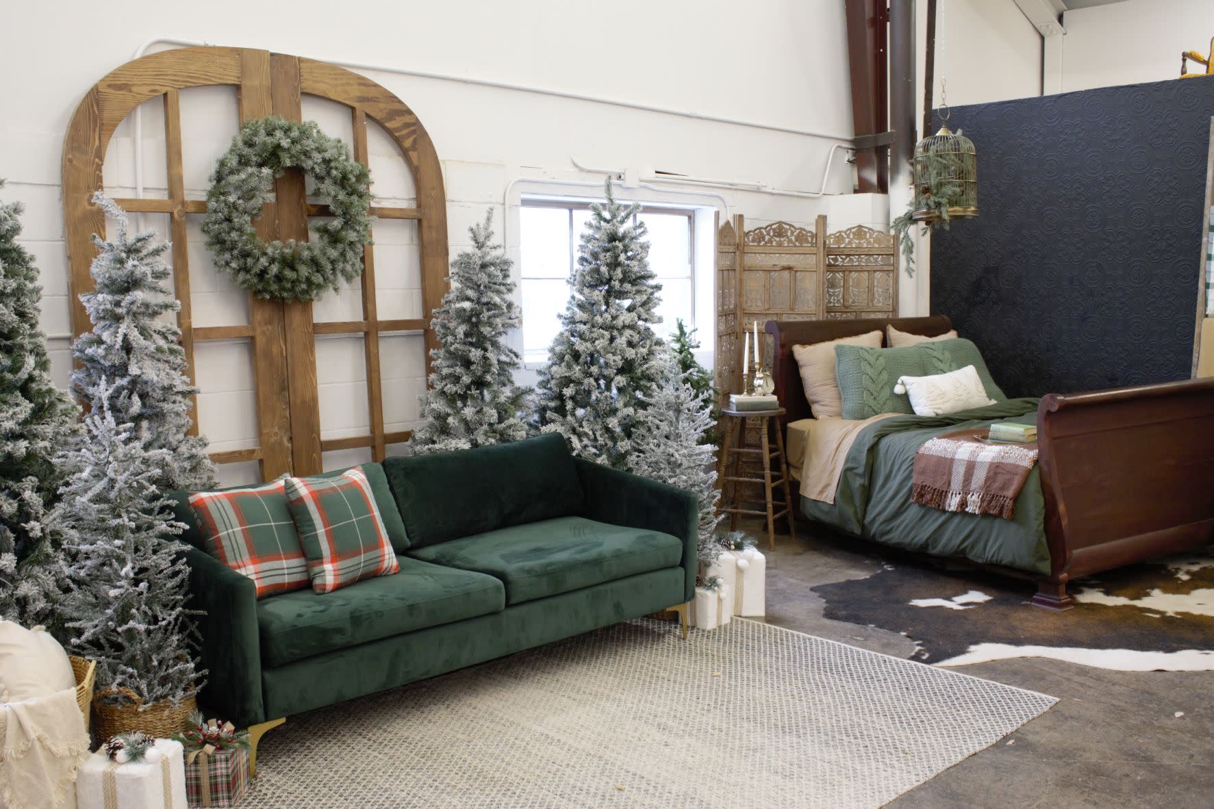A couple sits closely on a couch surrounded by decorated Christmas trees and wrapped gifts.