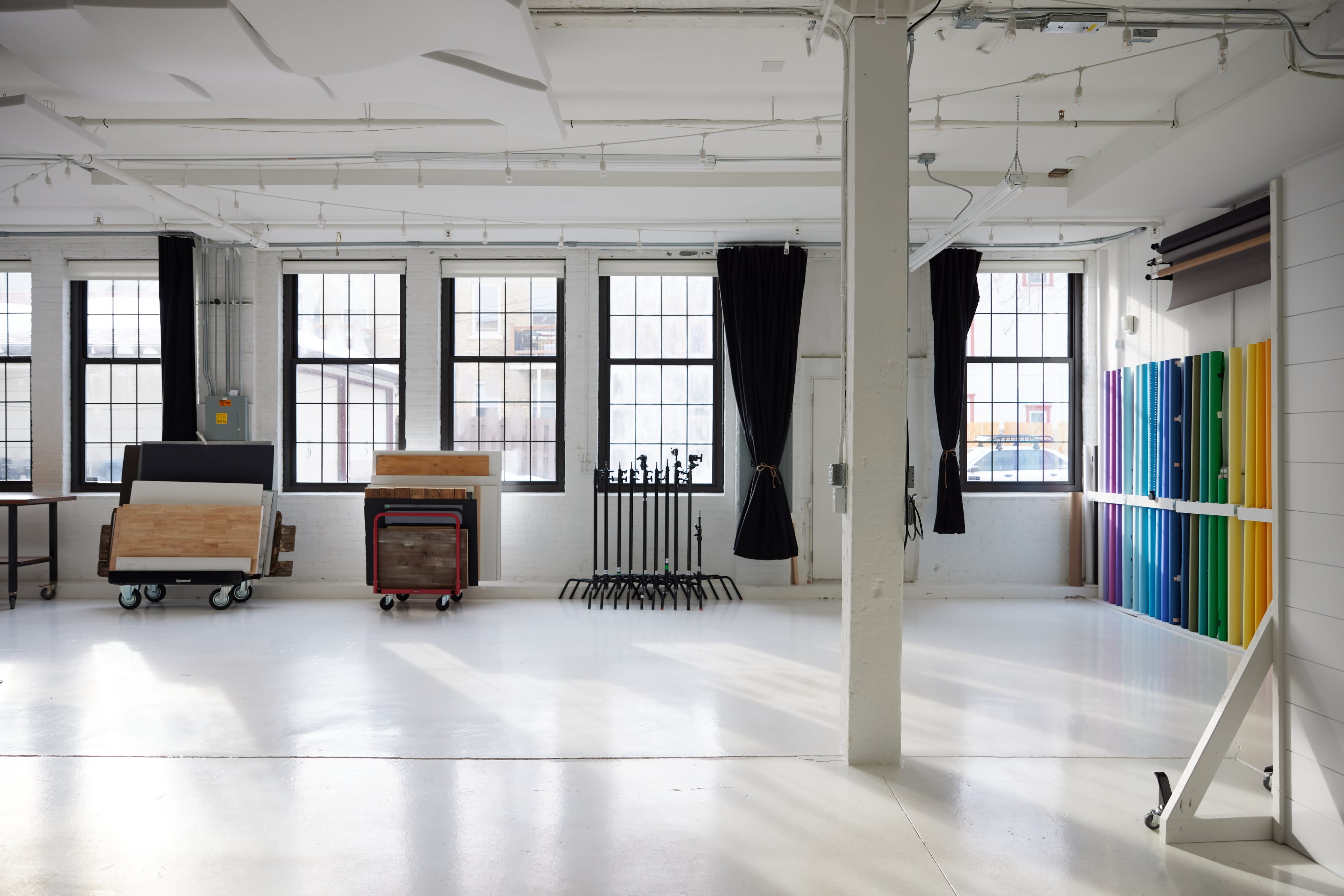 Four women sit in a cross-legged position on yoga mats, practicing meditation in a bright, airy room with large windows.