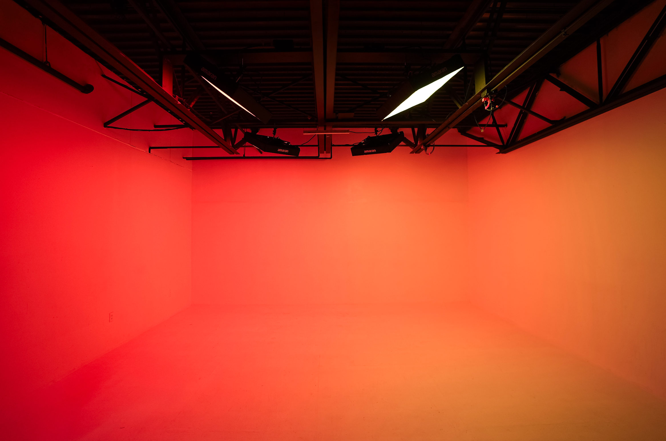 A model poses in front of a large reflector while a photographer captures the shot and an assistant adjusts equipment.