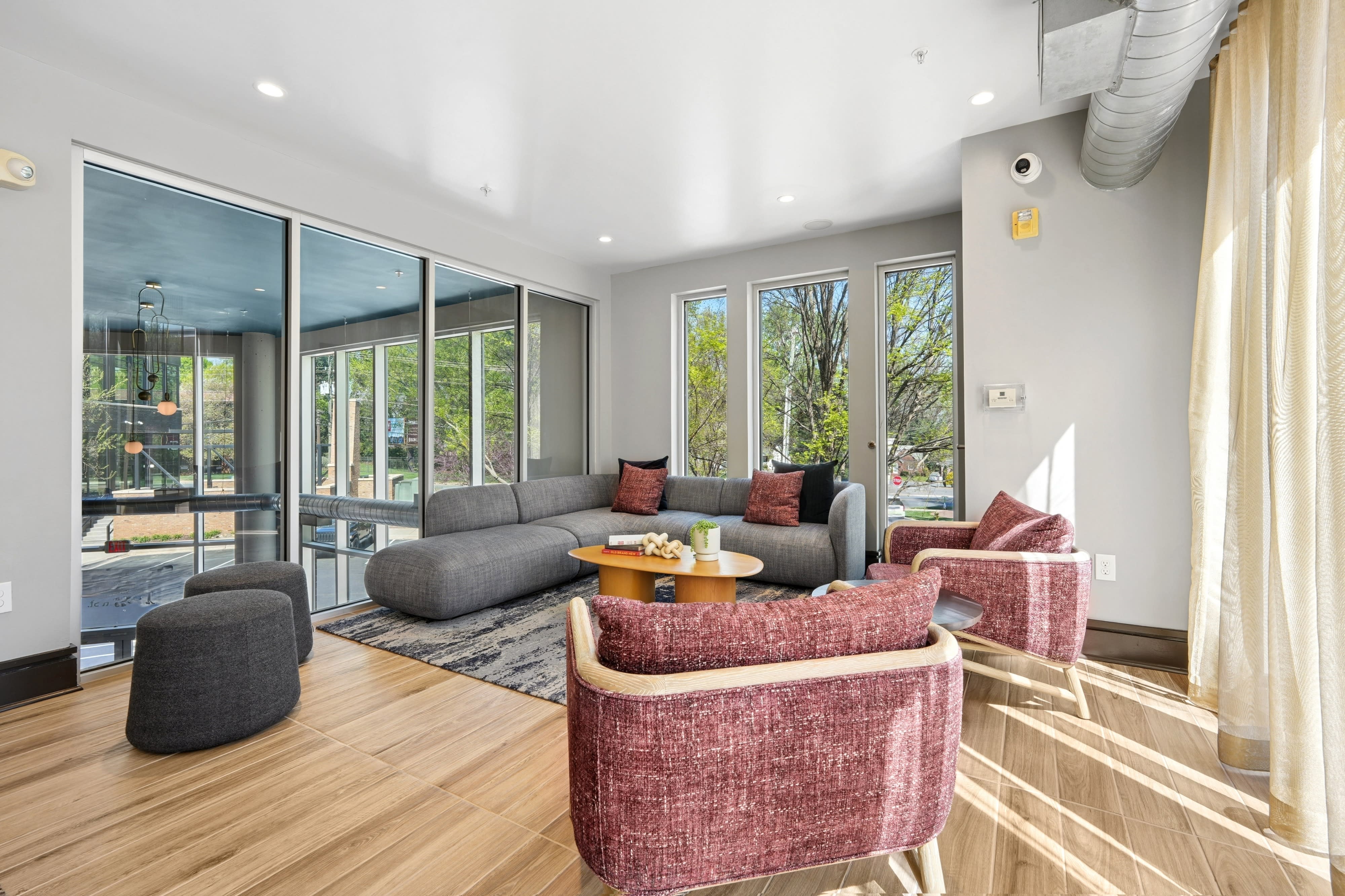 A modern common area features a leather couch, a wooden dining table, and various seating arrangements under contemporary lighting.