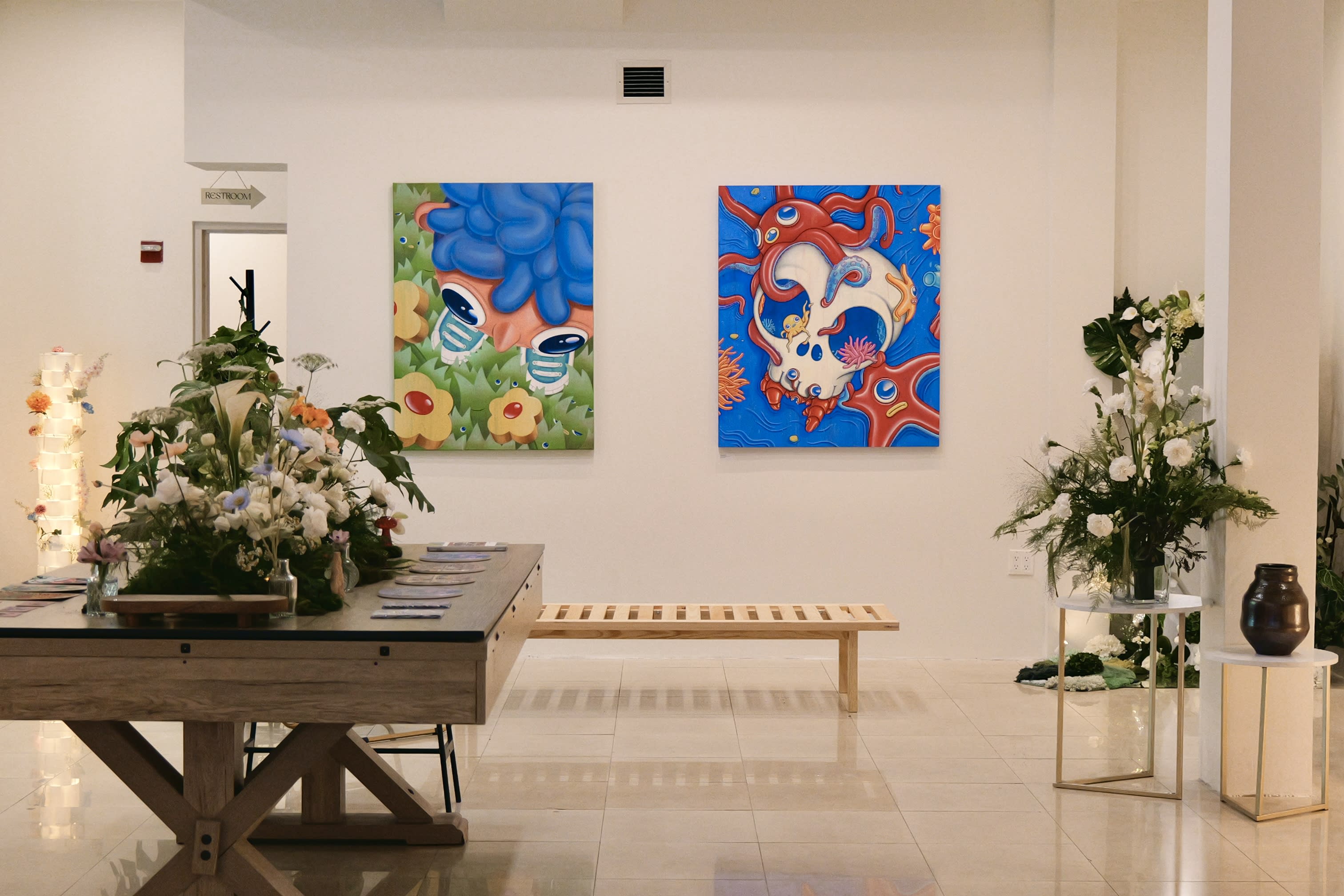 A group of people engages in conversation while examining artwork at an art gallery event.