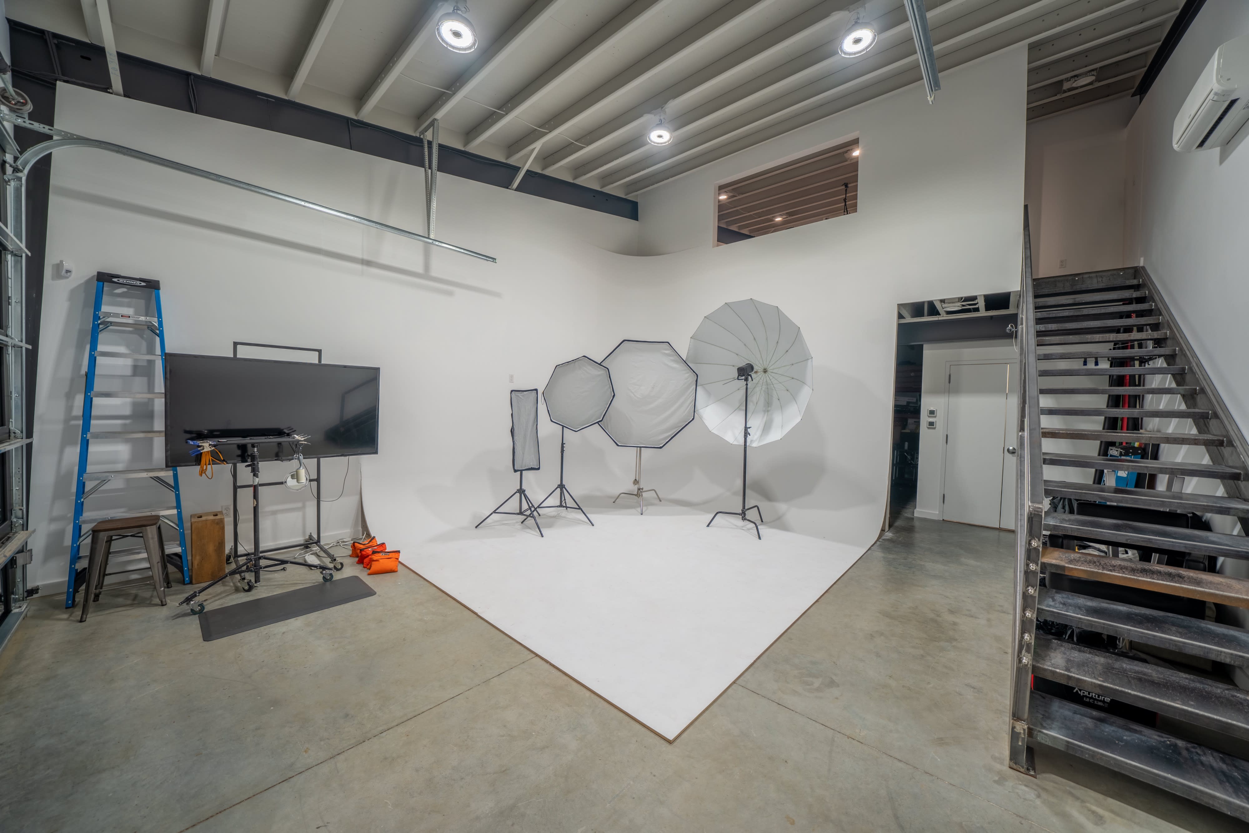 A photographer captures images of a model standing in front of a lit backdrop in a studio setup.