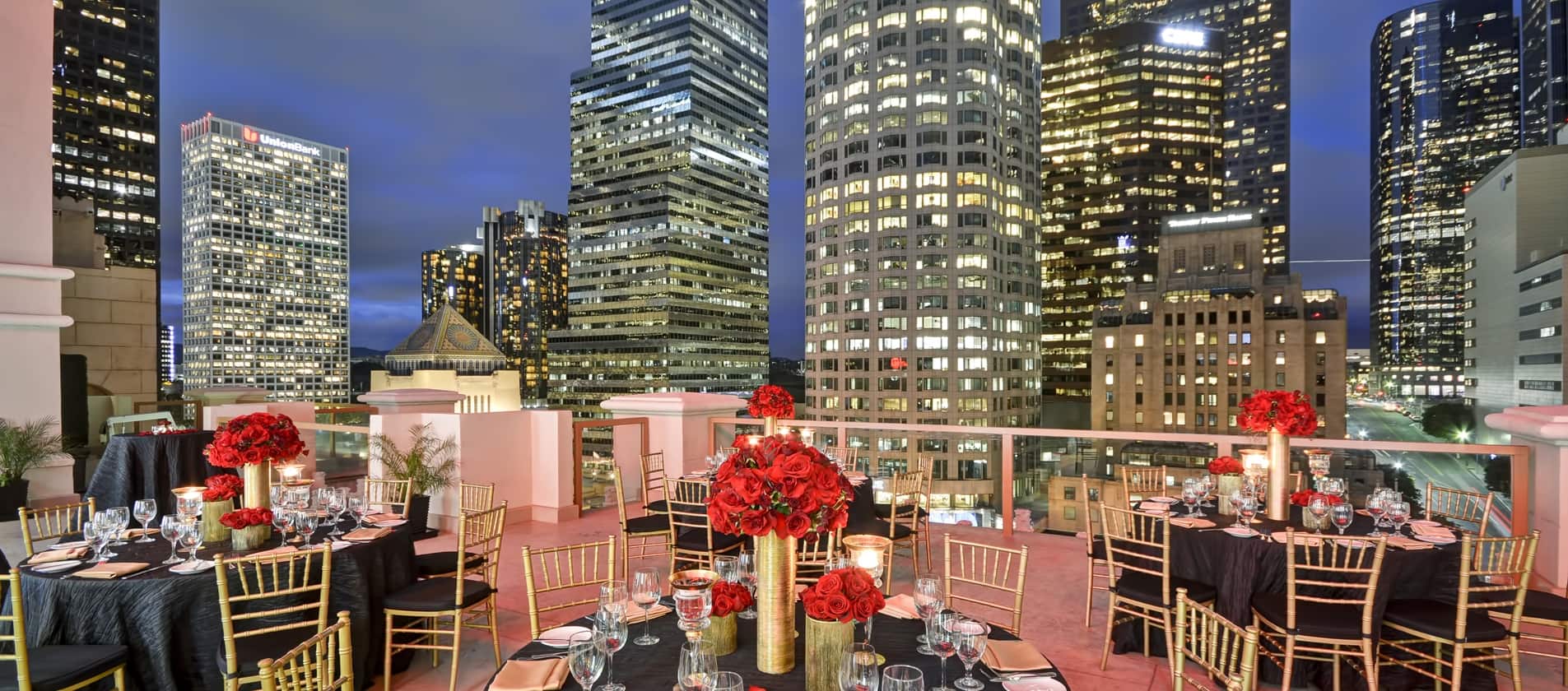 A rooftop celebration features turquoise and white balloons with a view of tall skyscrapers.
