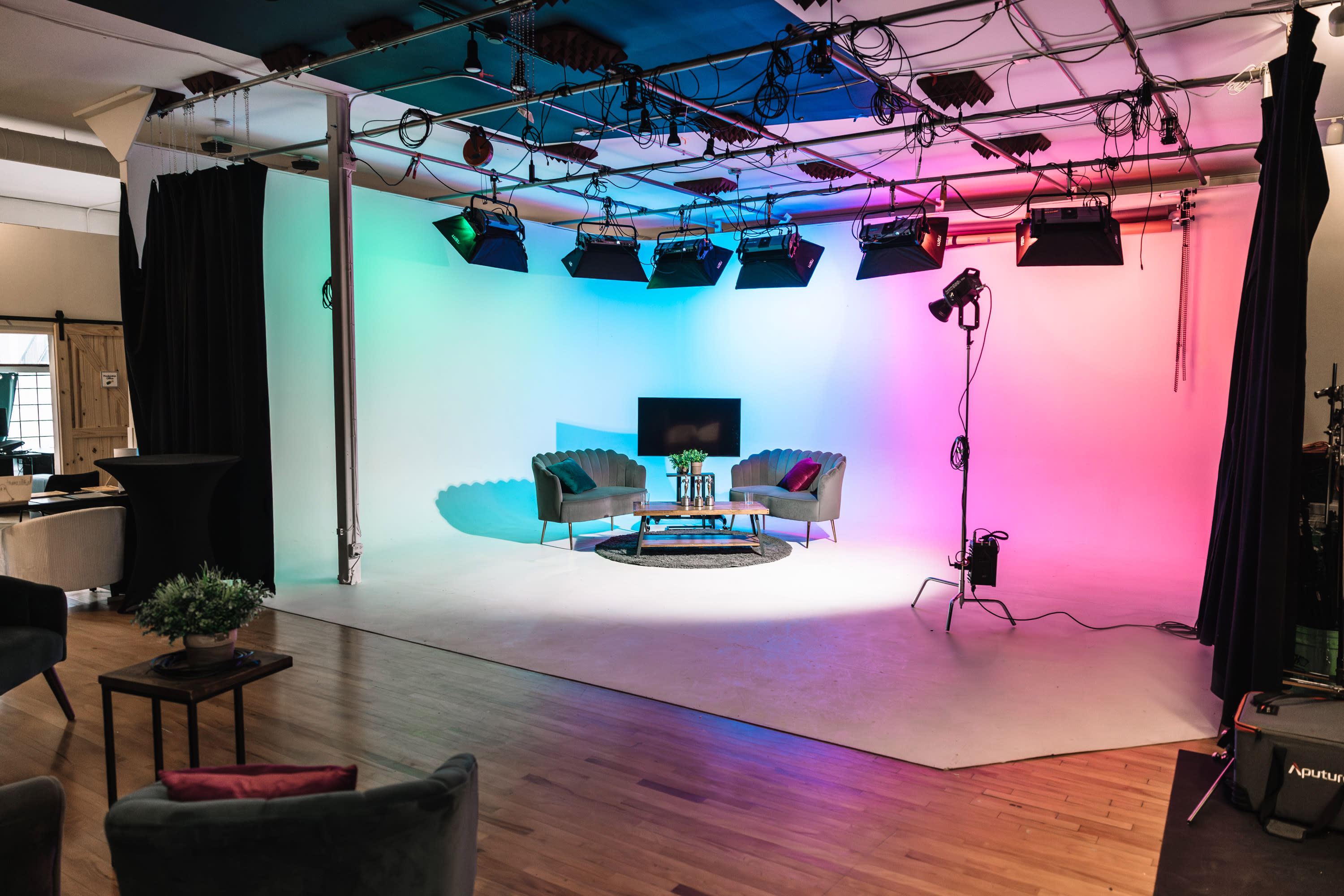 A group of dancers performs on white draped platforms in a studio setup for a video shoot.