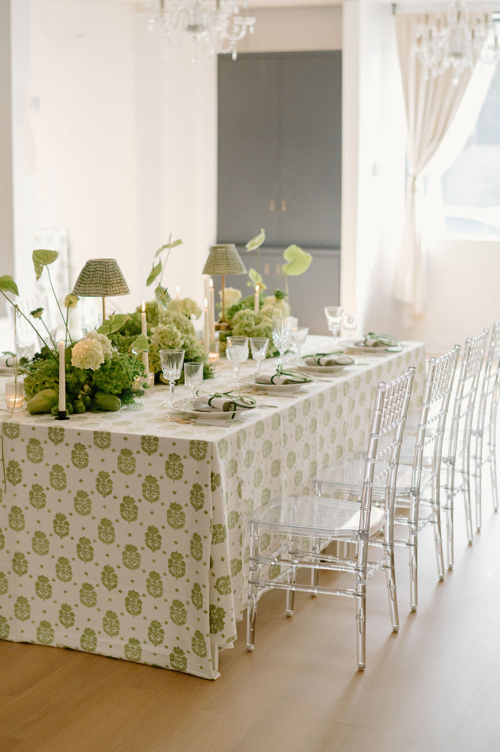 A table displays an assortment of desserts, including pastries and a decorated cake, set against a colorful floral backdrop at a bridal shower.