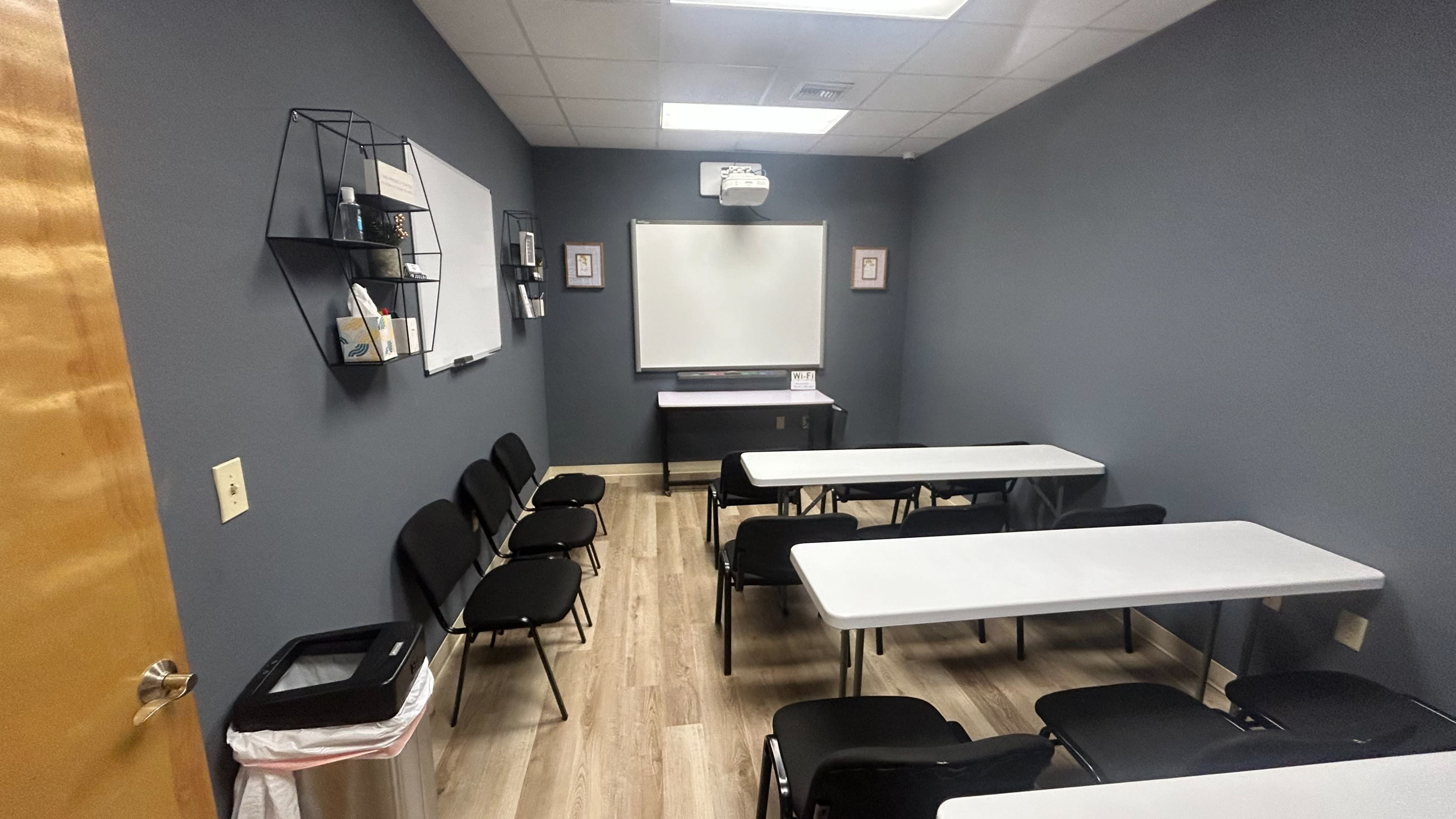 A group of people poses together in a meeting room, holding new backpacks as part of a charity event.