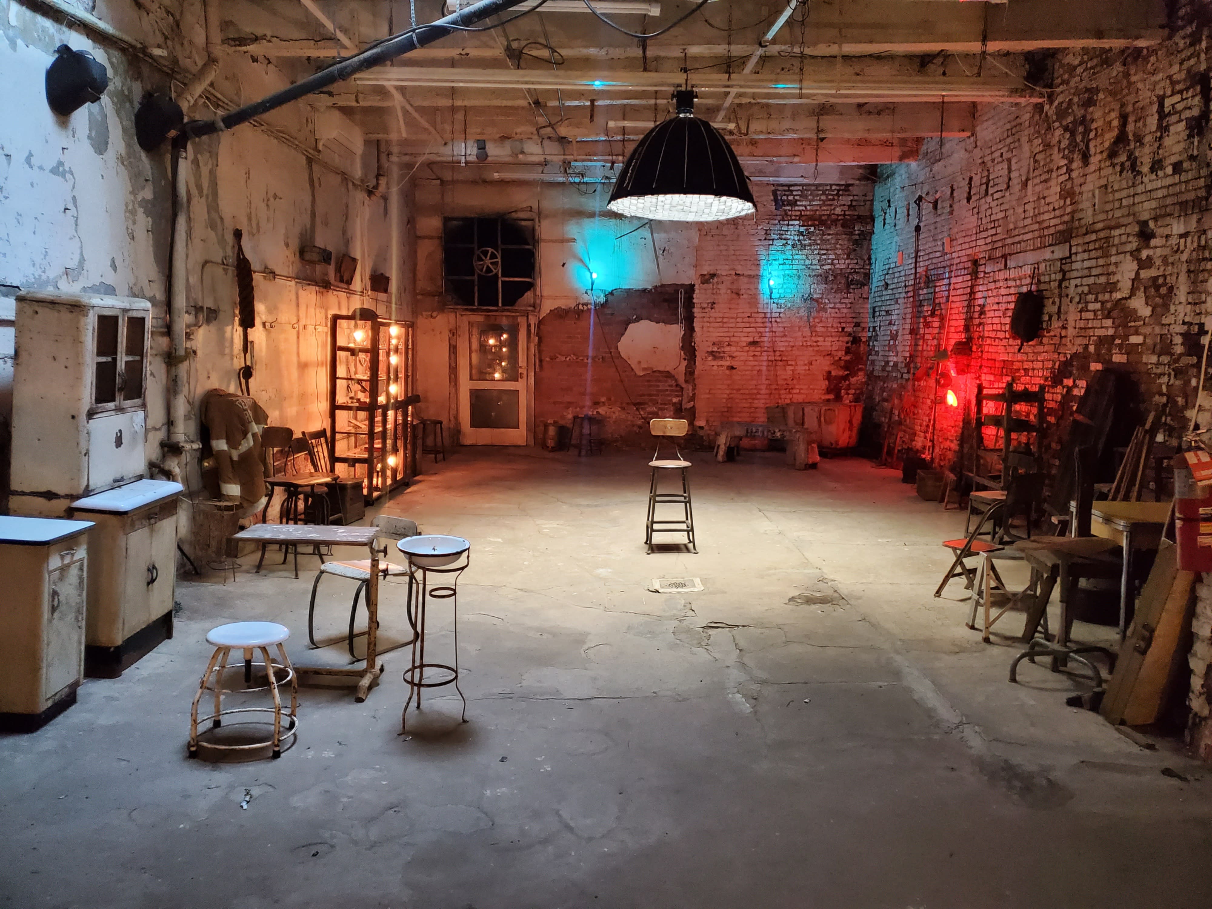 A videographer captures a drummer performing in a dimly lit, red-tinted industrial space.