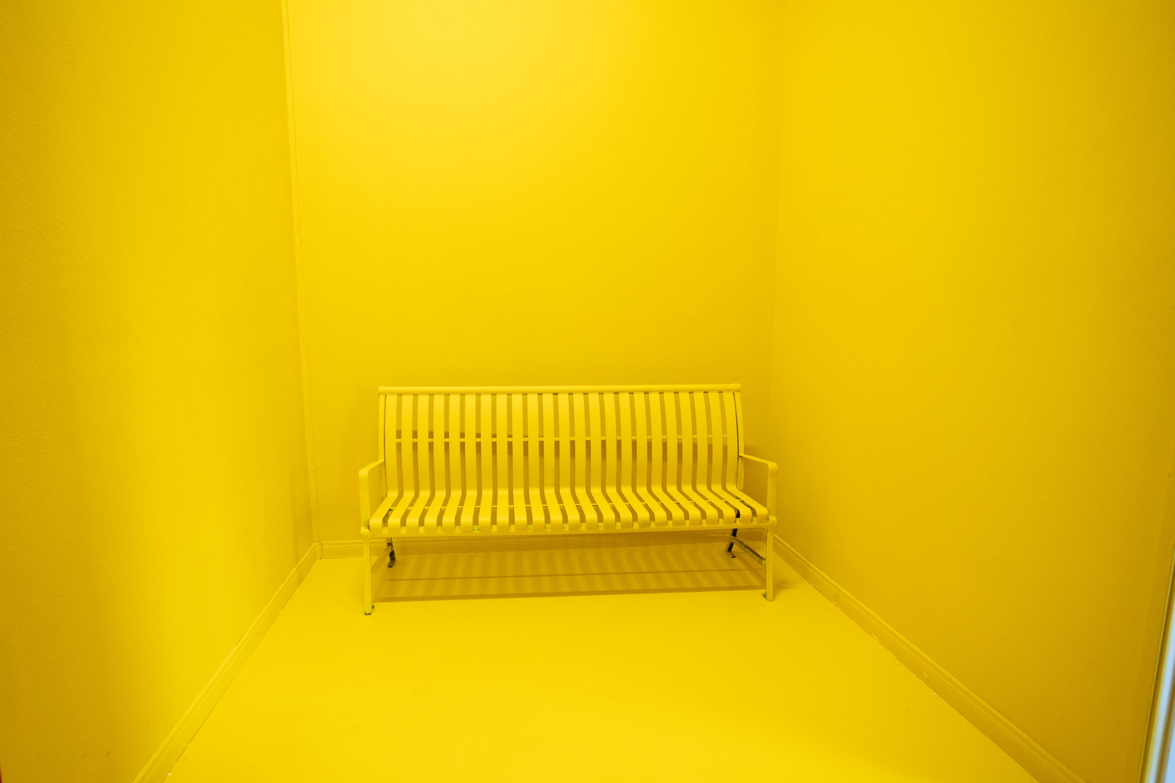 A model poses confidently in a bright yellow gown against a matching backdrop.