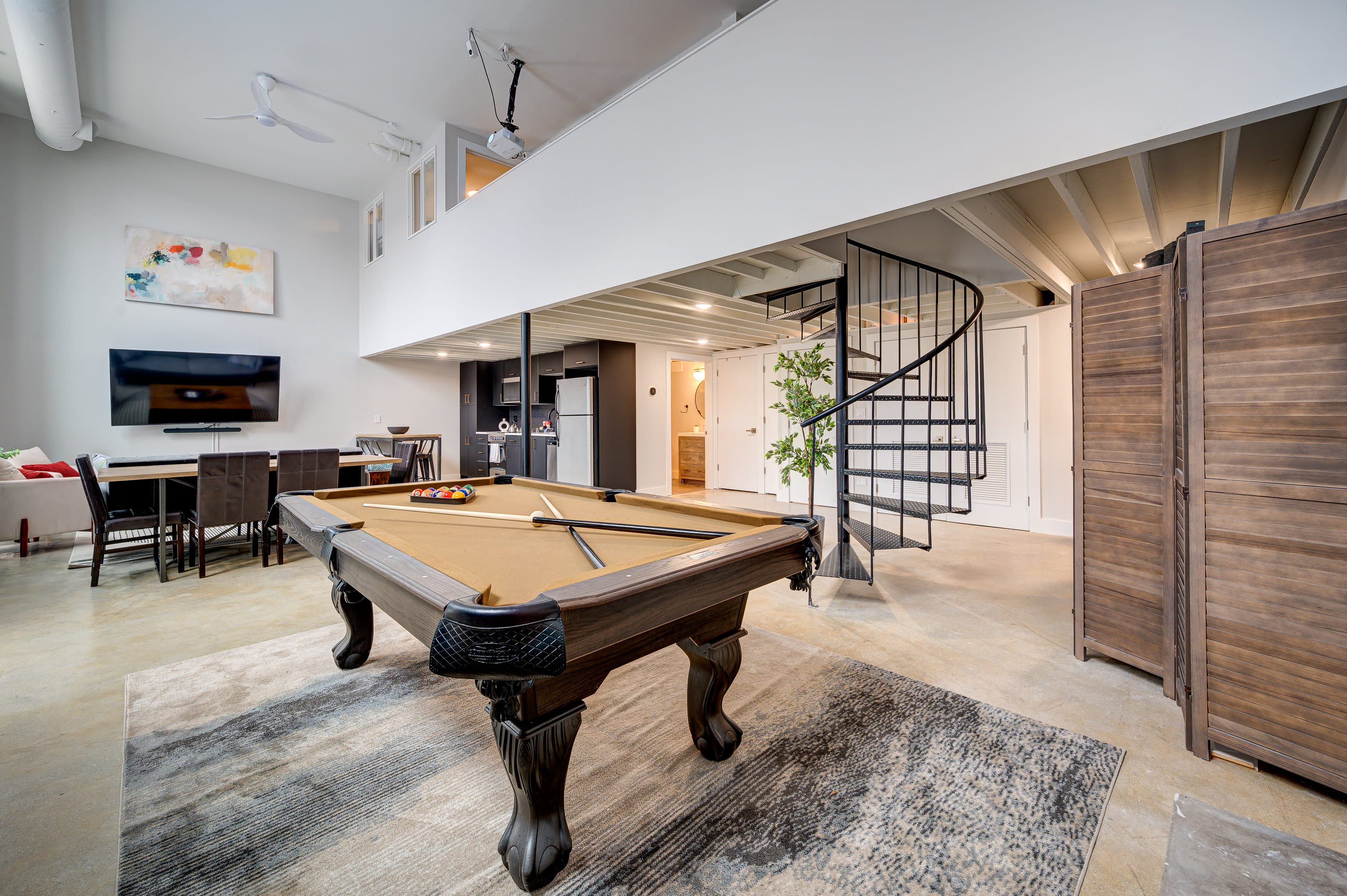 A man in a suit leans against a pool table in a stylish room.