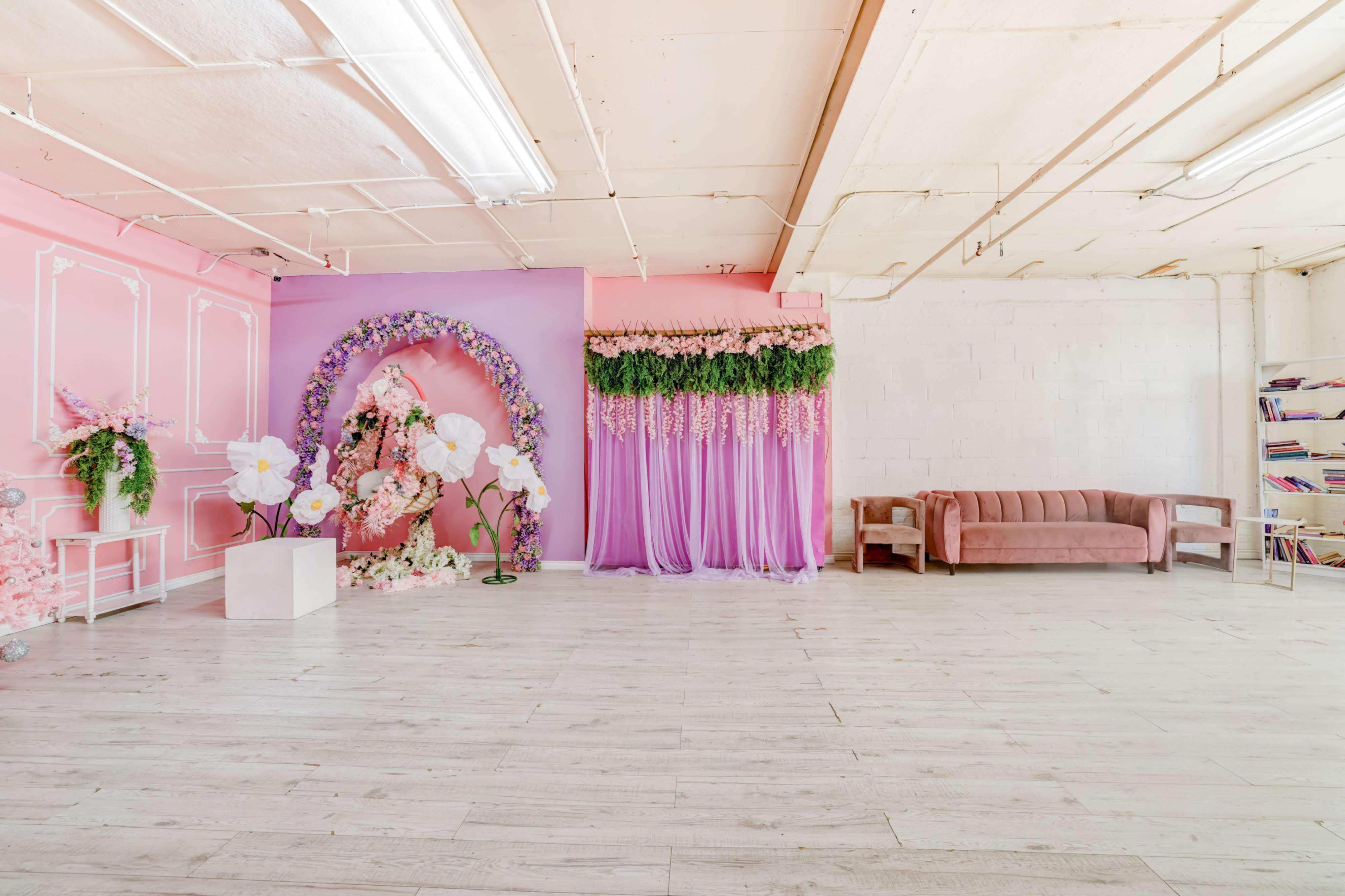 A model poses elegantly at a white piano adorned with flowers, wearing a vibrant blue dress and pink boots.
