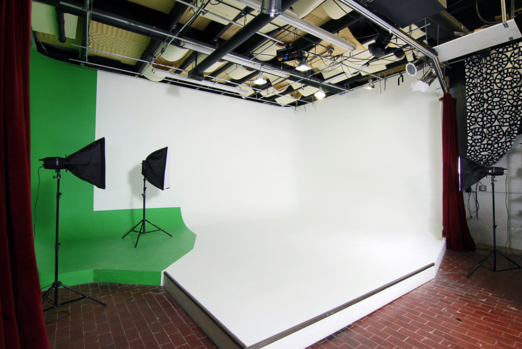 A couple poses closely together for a photo shoot against a simple gray backdrop.