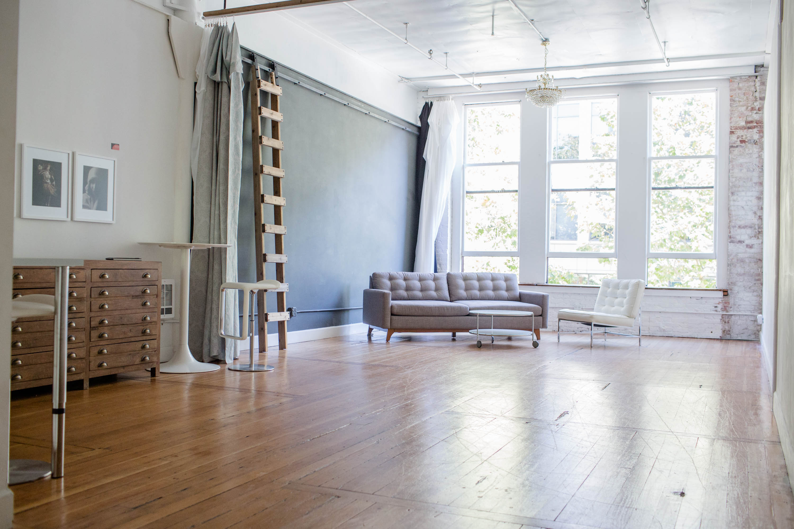 A person sits on a wooden floor in a casual pose during a photo shoot.