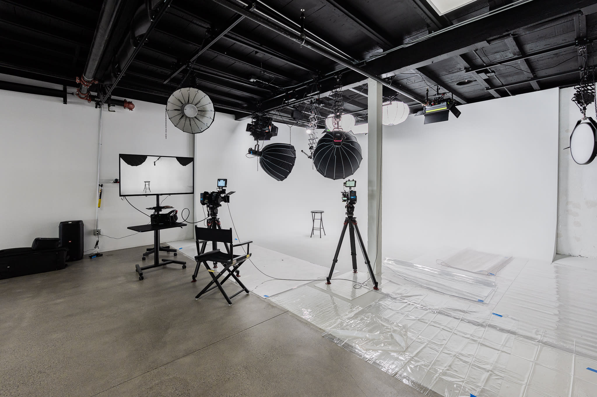 A photographer captures two models posing on their stomachs in a studio with a white backdrop.