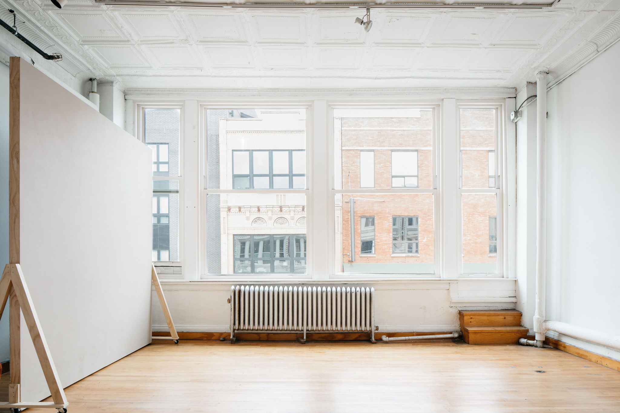 A photographer captures a model posing by a large window in a bright room.