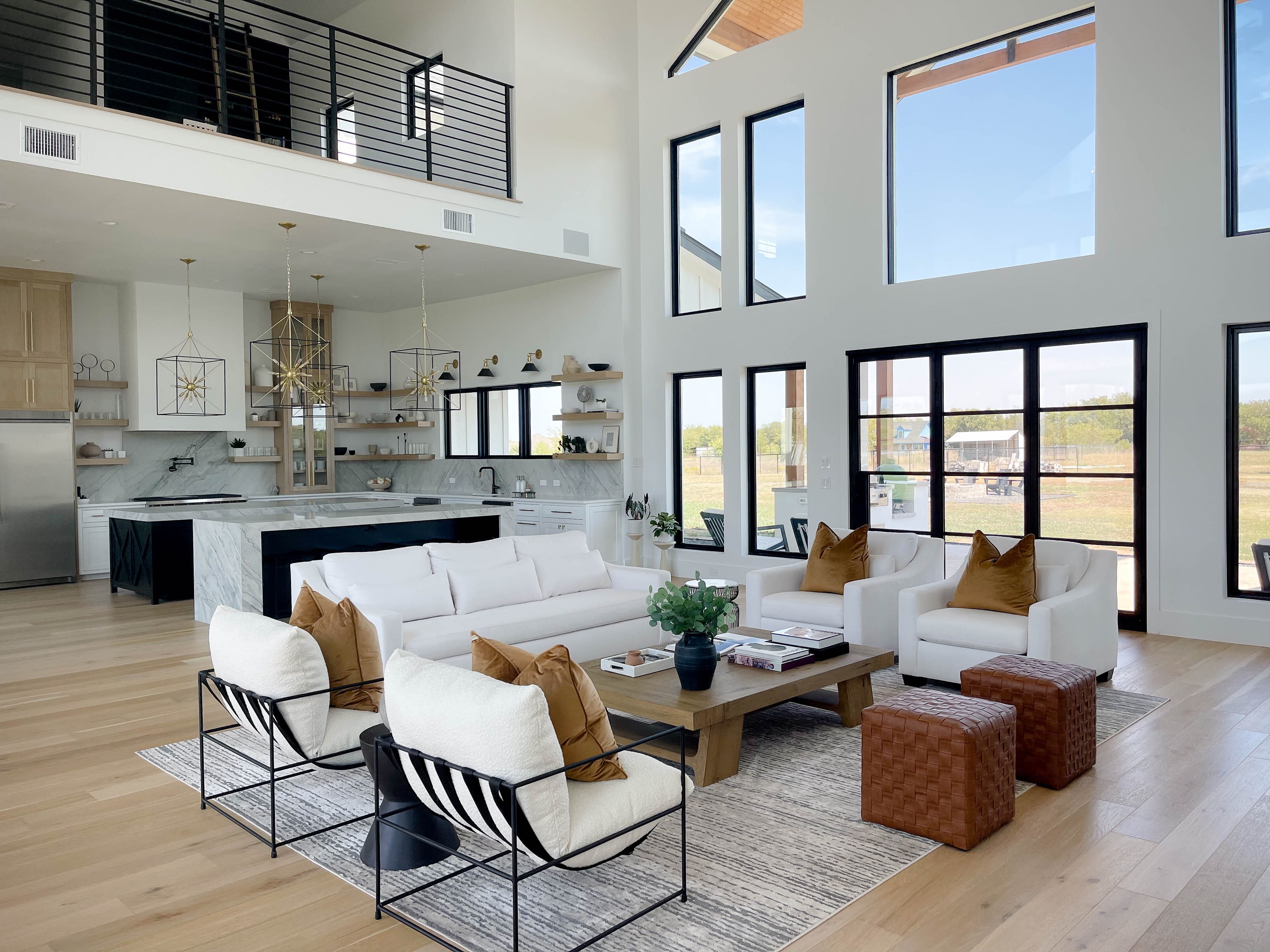 A person poses thoughtfully at a marble kitchen island beneath modern pendant lights.