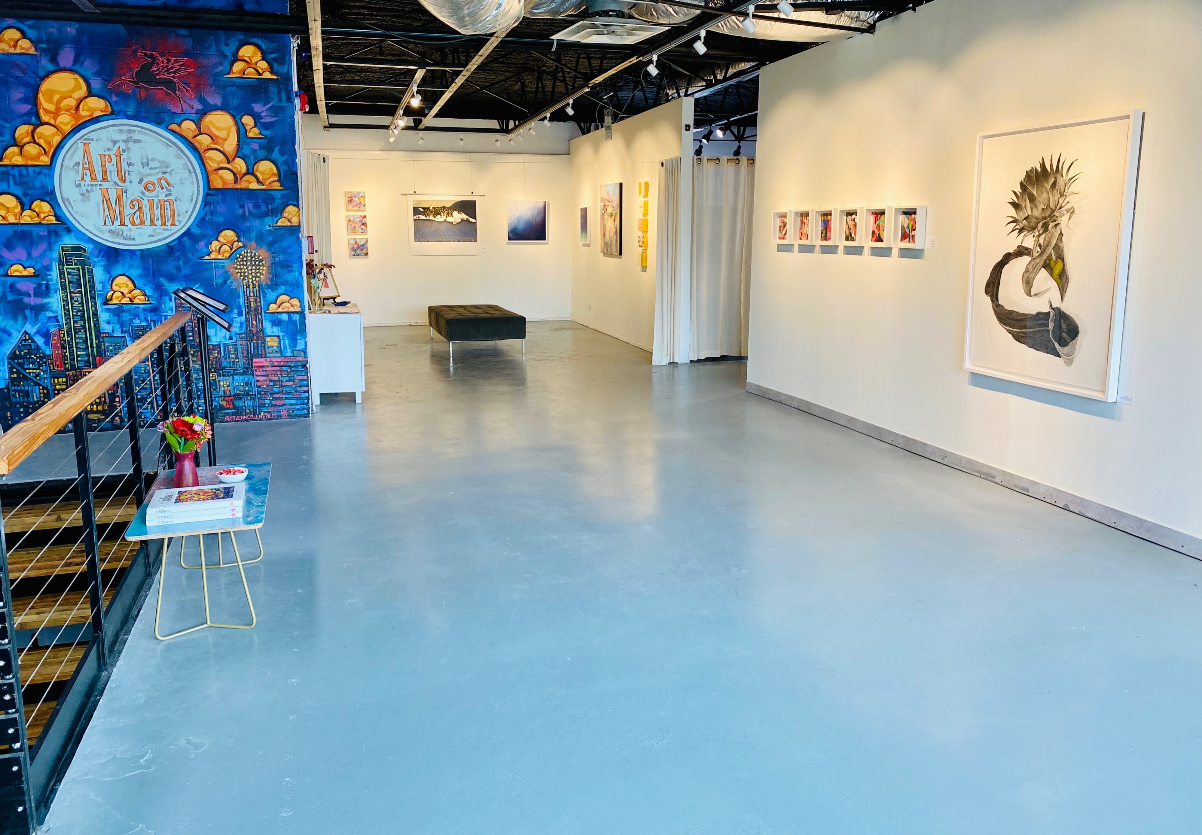 A person stands in an art gallery, observing various framed artworks displayed on the walls.