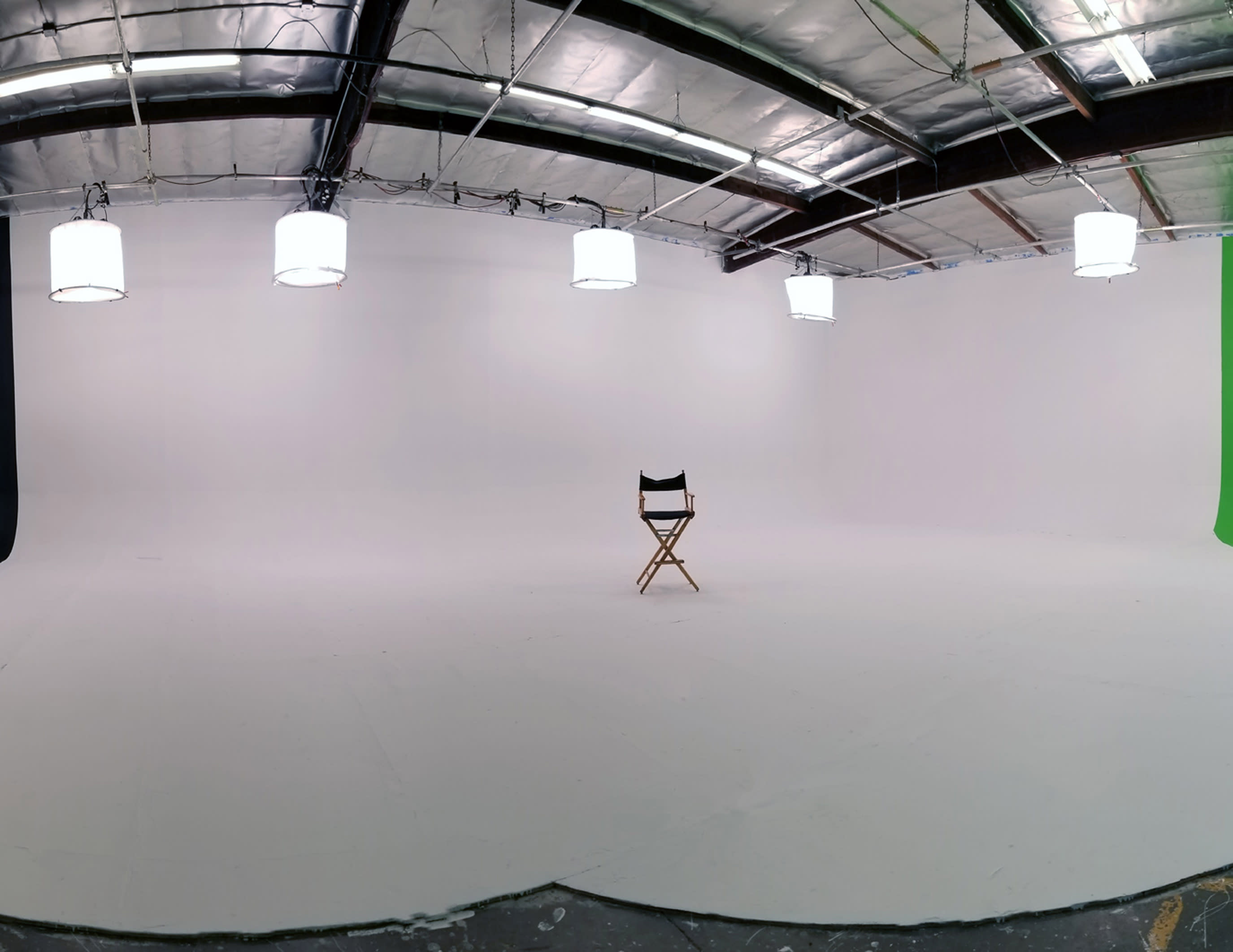 A silhouette of a dancer strikes a pose in a well-lit studio, framed by dark curtains and equipment.