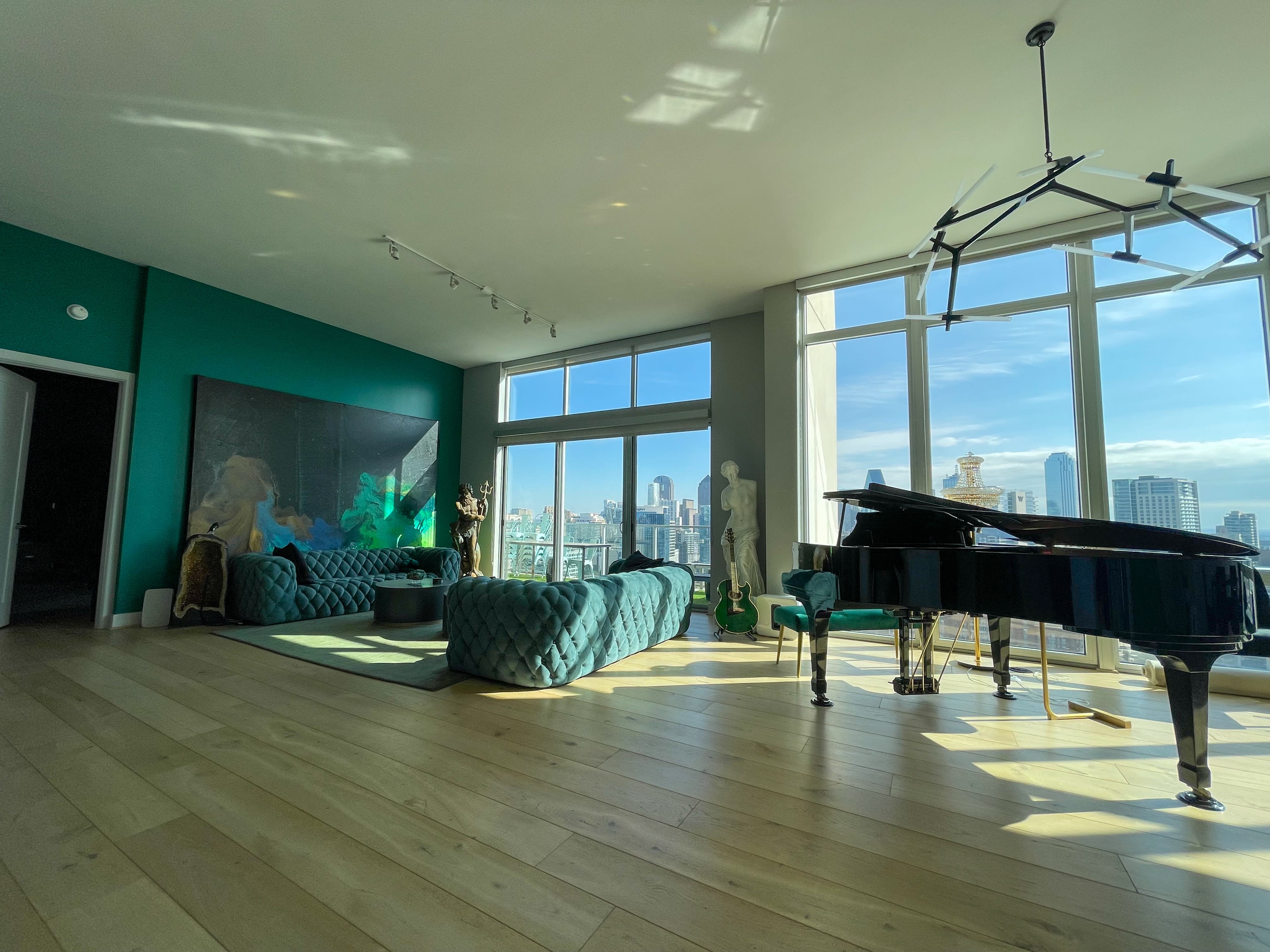 A photographer captures a model in a light blue gown seated on a green rug in a well-lit room.