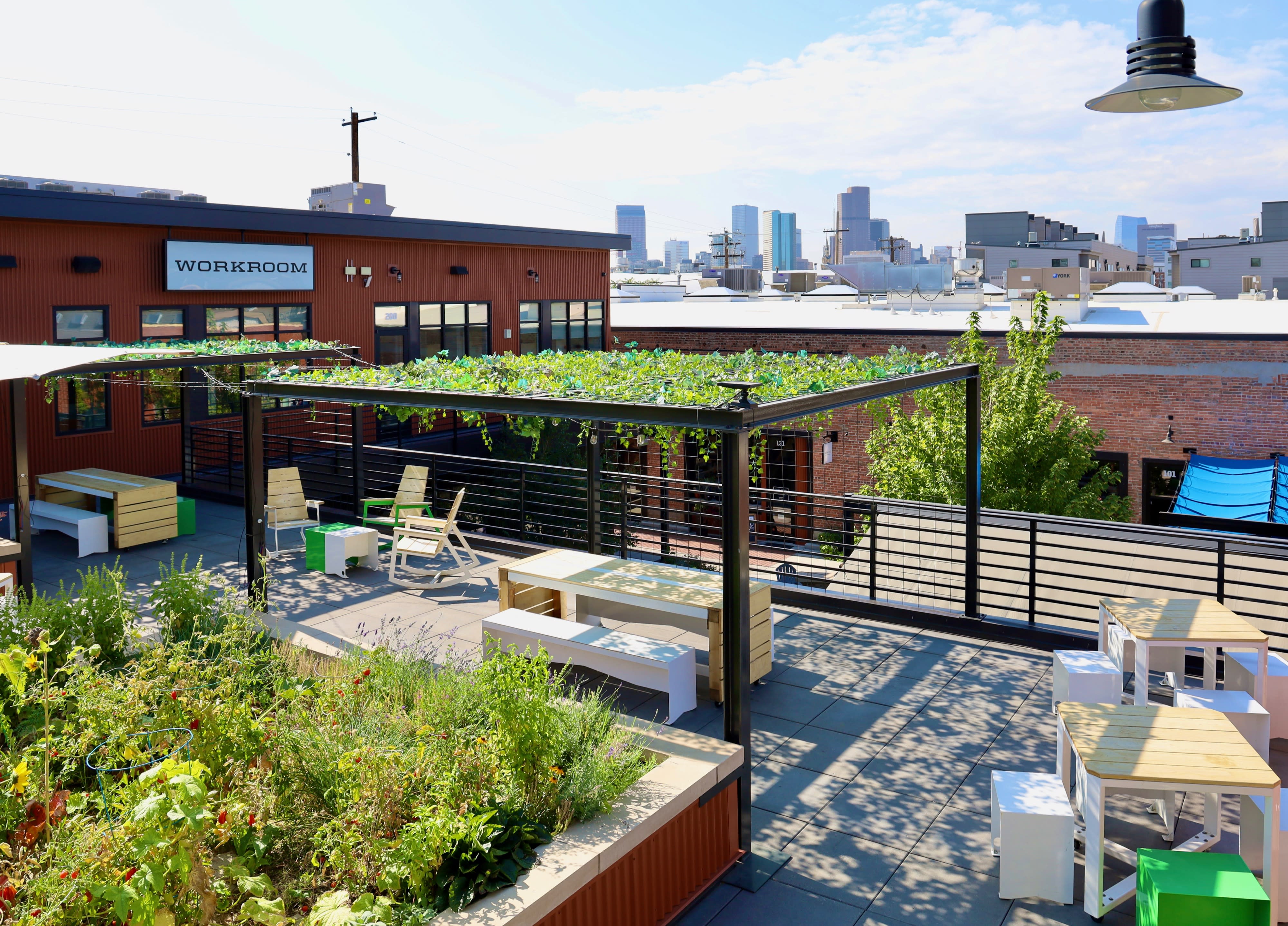 People socialize and enjoy drinks at a welcome party on a rooftop as the sun sets in the background.