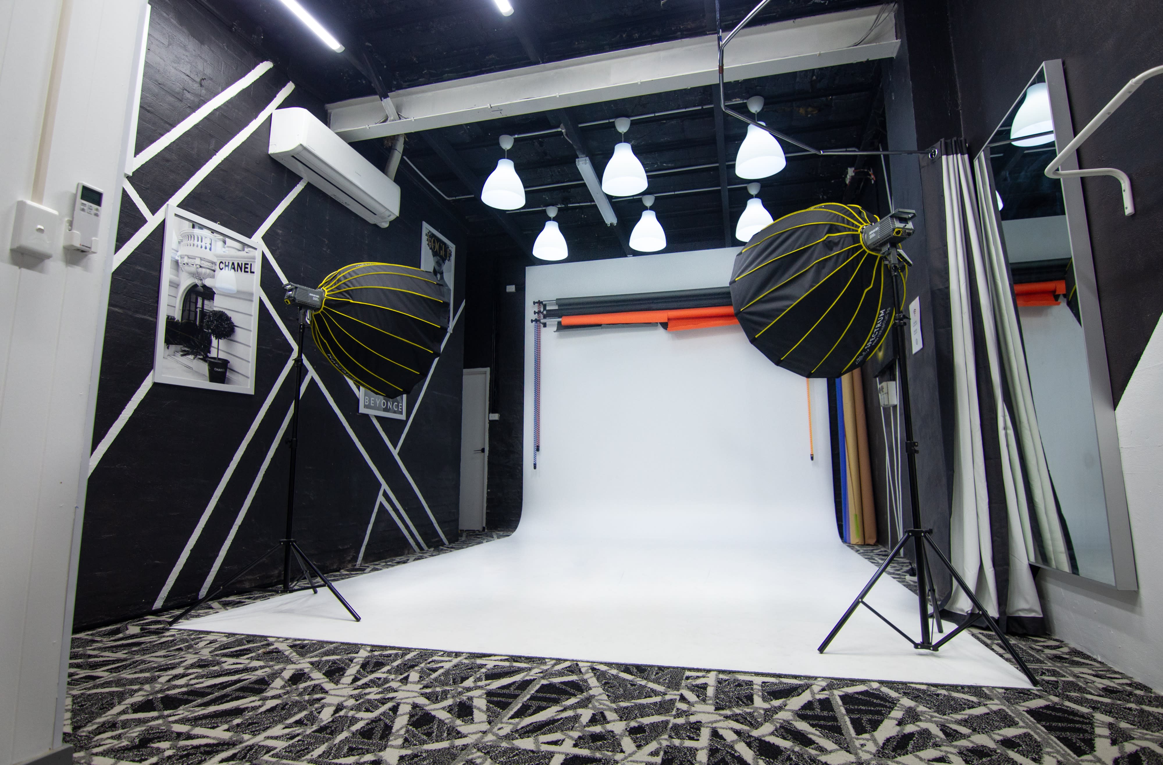 A person sits in front of a black backdrop, surrounded by multiple camera and lighting equipment for an interview video shoot.
