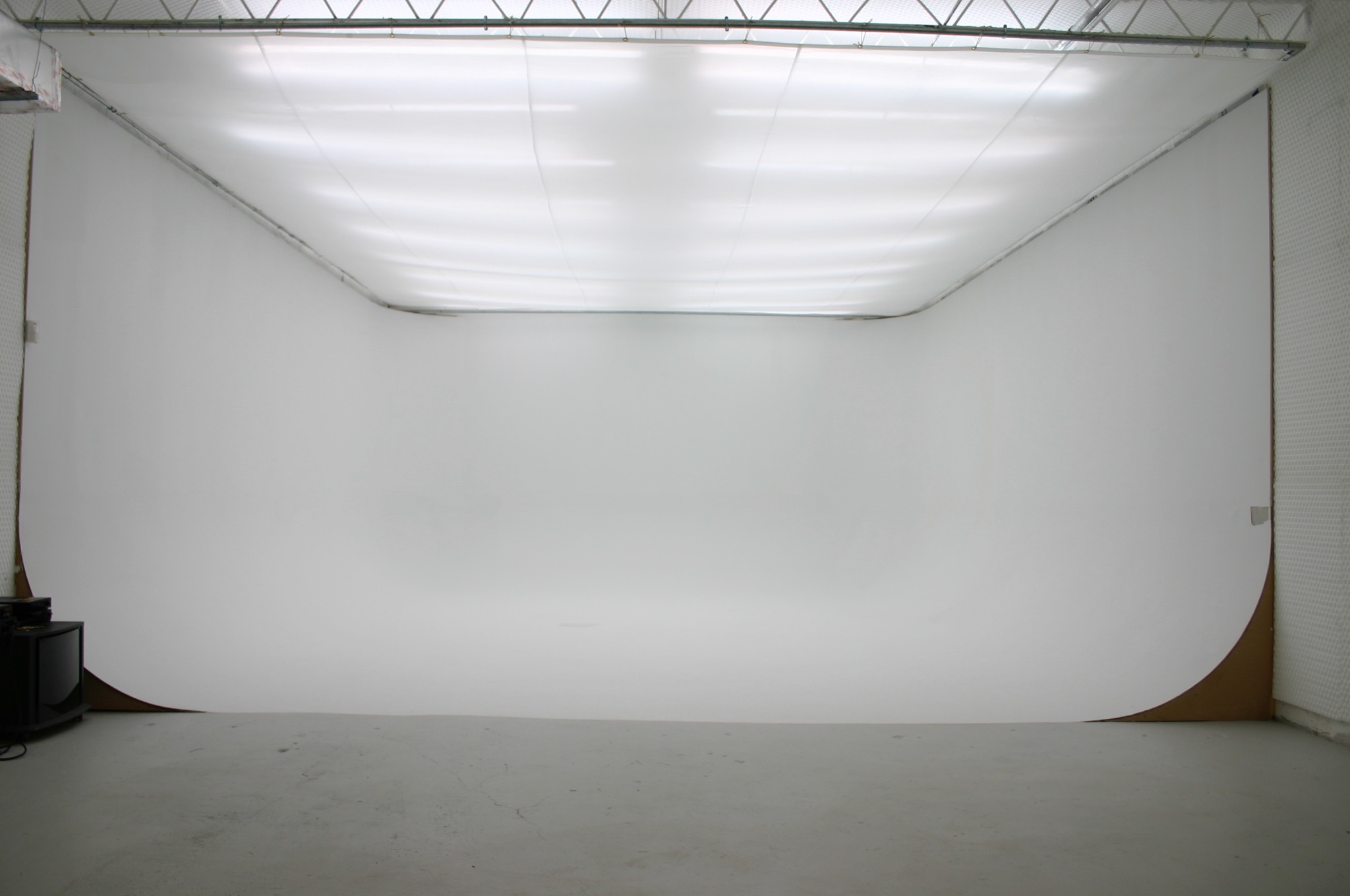 A band is performing a video shoot in a minimalist studio setting with a white backdrop, featuring a guitarist, bassist, and drummer.