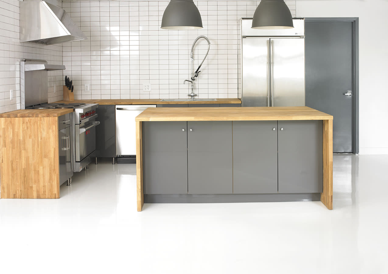 Two people are cooking together in a modern kitchen, standing at a stovetop with pots on the burner.