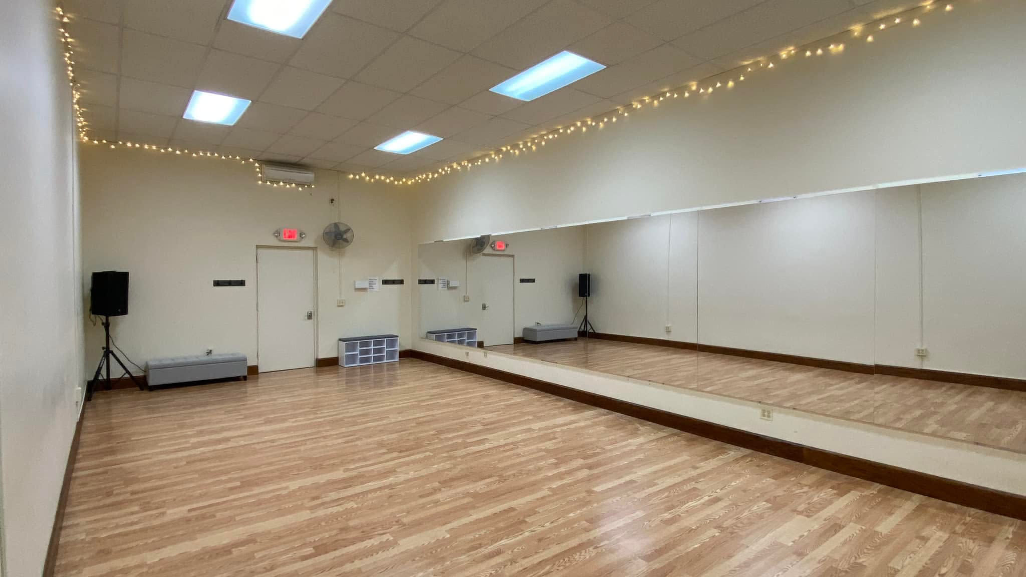A group of individuals participates in a Pilates class, engaged in various exercises on mats in a mirrored studio.