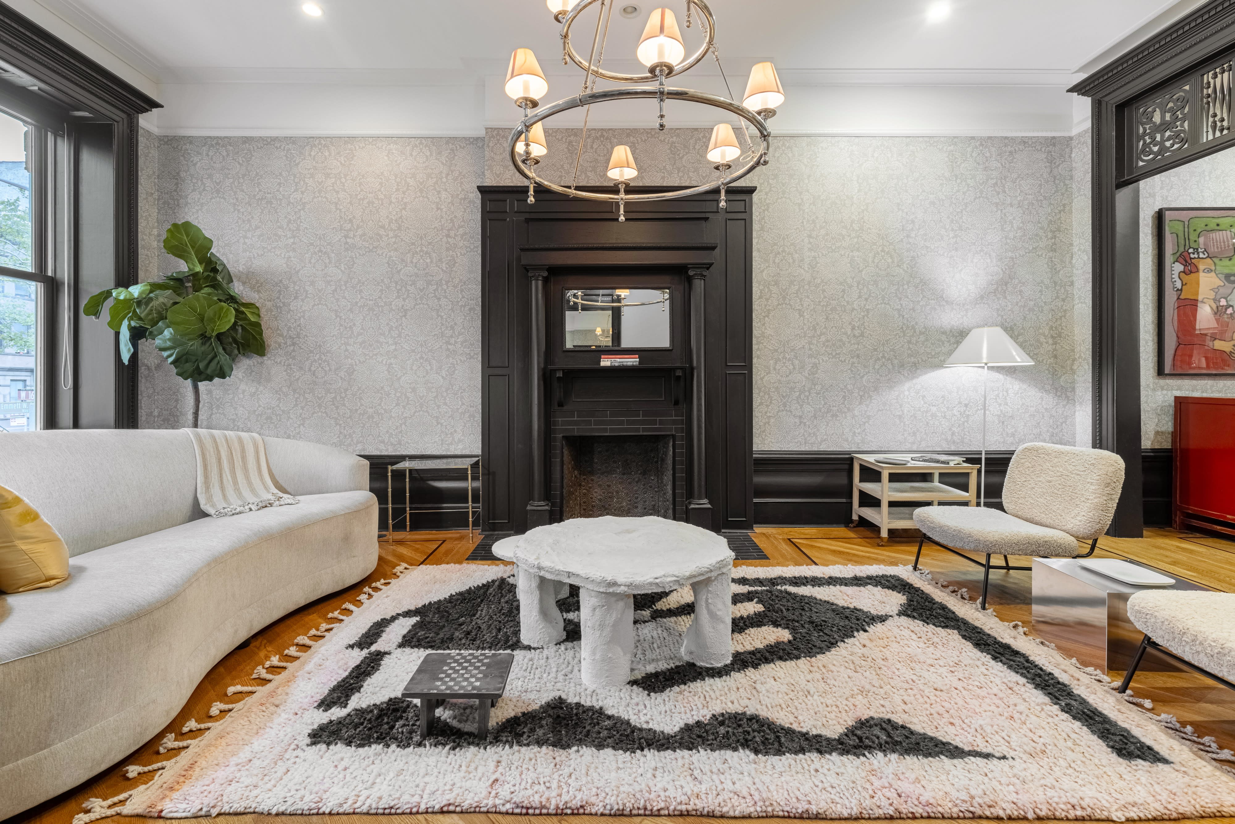 The scene features a video shoot in a stylish room where a host interviews a guest seated on a patterned rug.