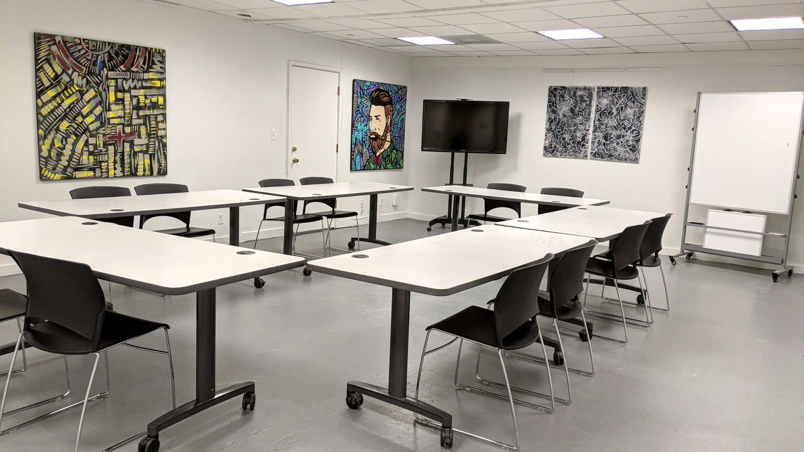 The art workshop features a spacious room with tables arranged for creative activities, surrounded by vibrant wall murals.