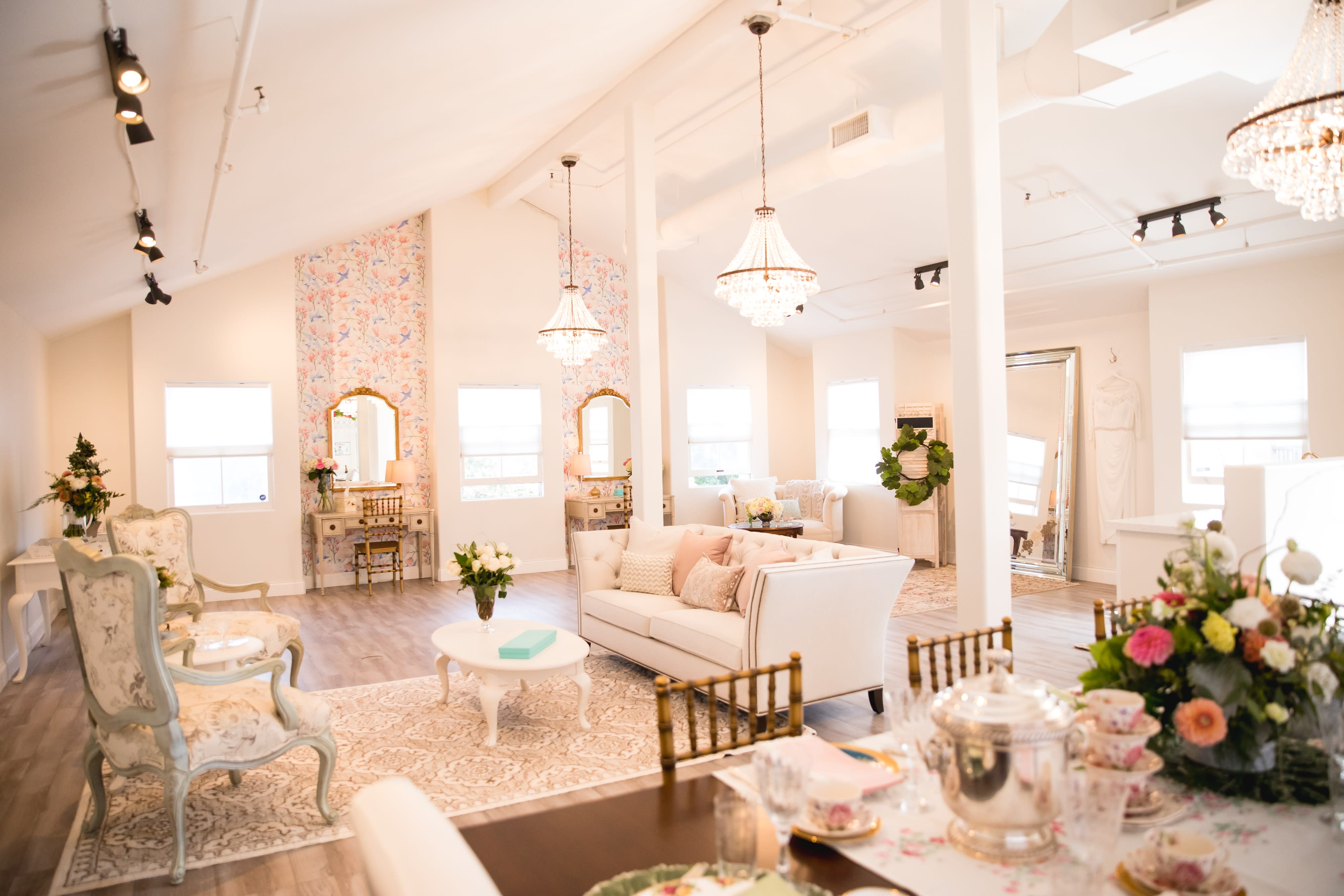 The scene features a decorated table with a sign reading "Taylor's Bridal Shower," surrounded by floral arrangements and a spread of food, including pastries and a charcuterie board.