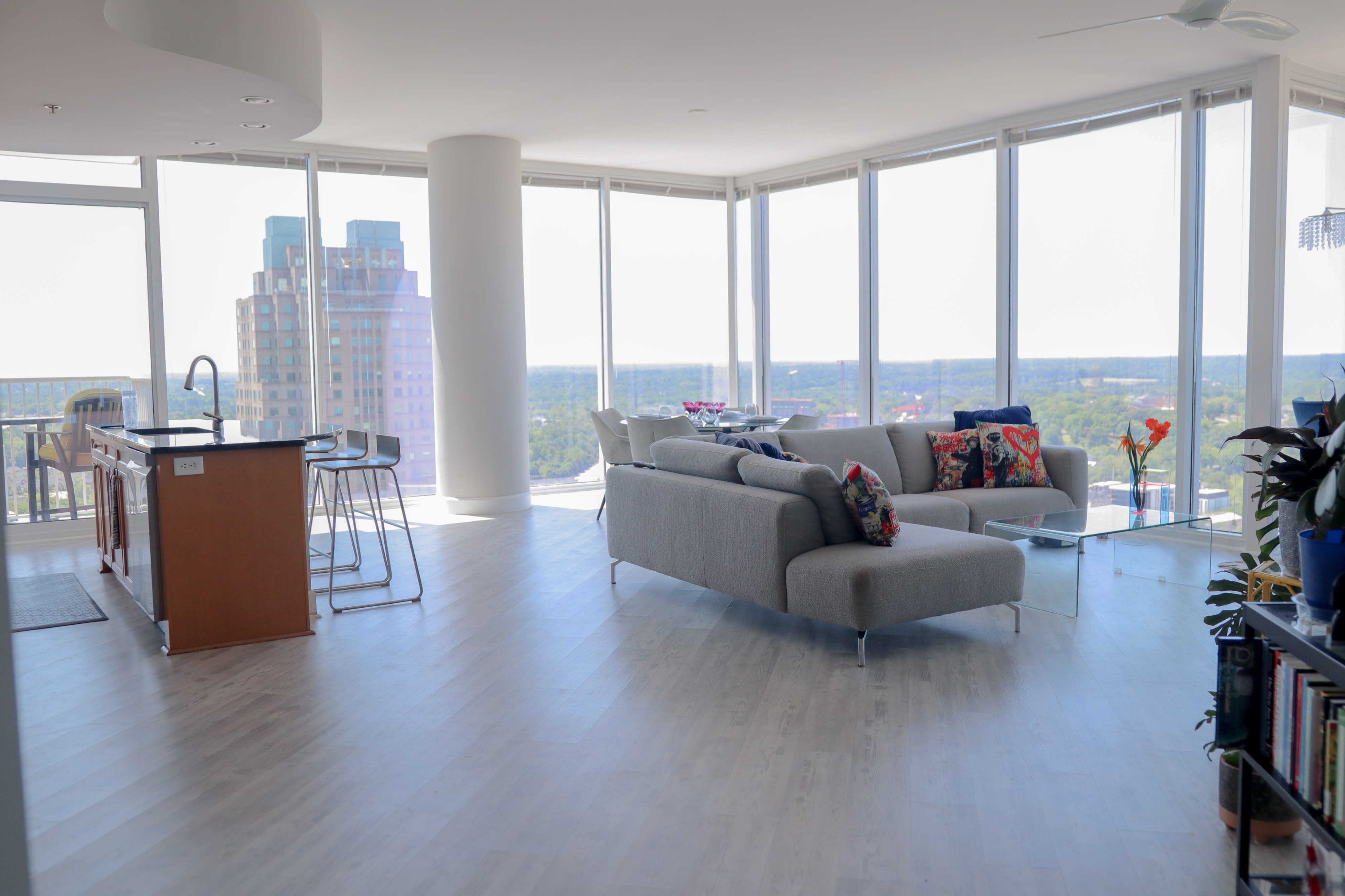 A camera is set up in a modern apartment, facing a sunset visible through large windows.