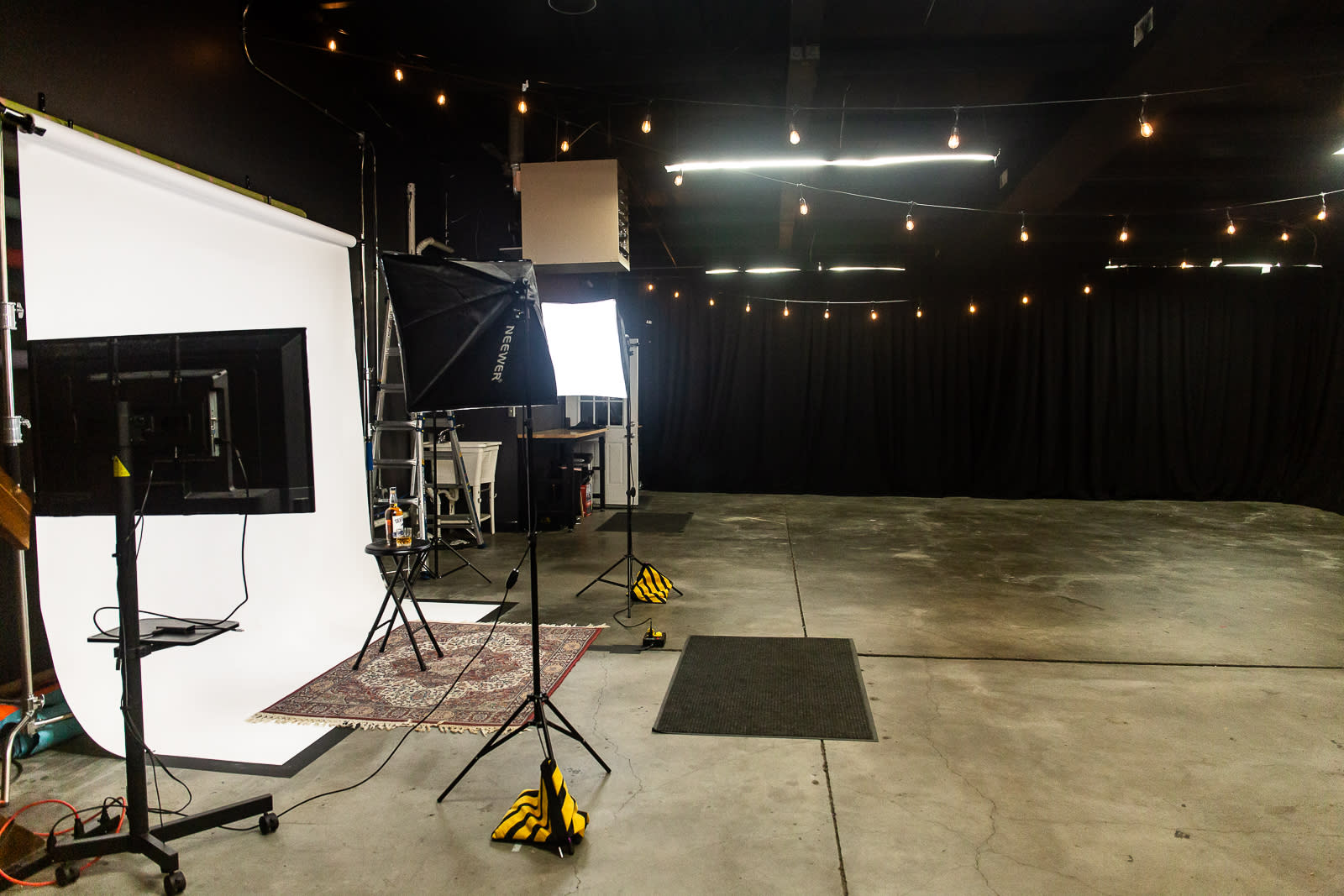 A camera operator records a singer performing on stage in a dimly lit studio surrounded by art supplies and decor.