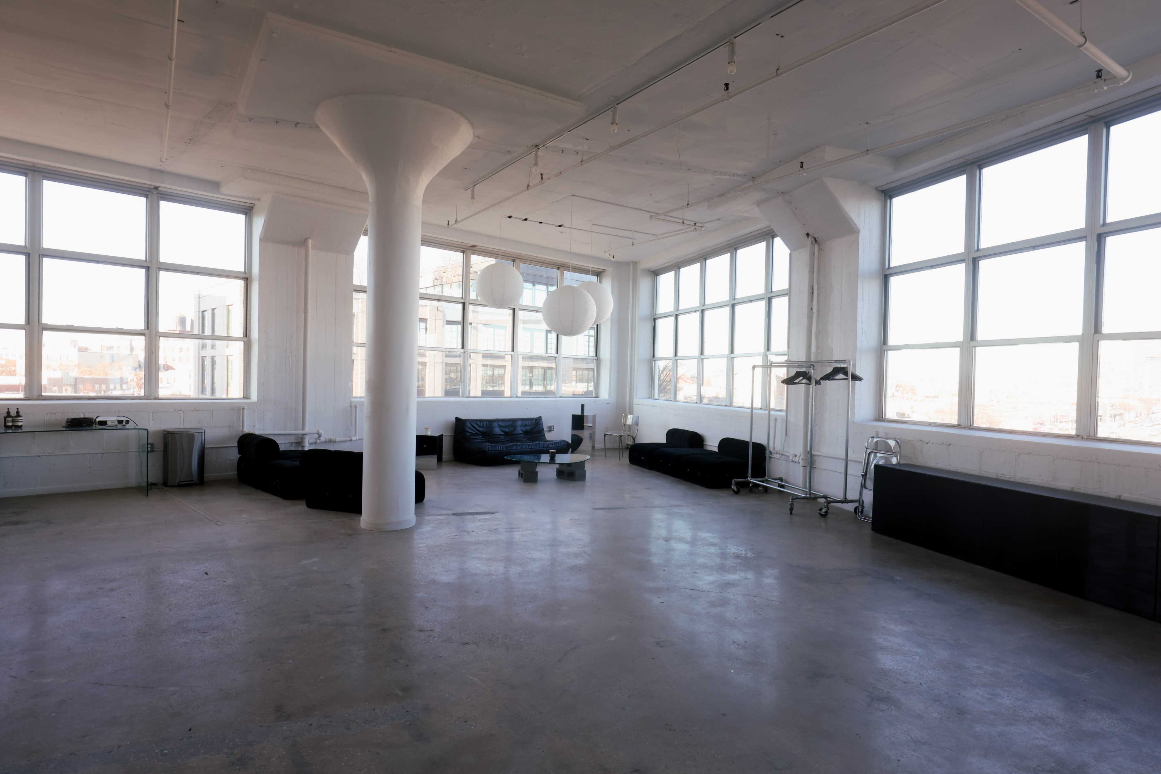 A well-lit studio features large windows, scattered props, and equipment for a photoshoot.