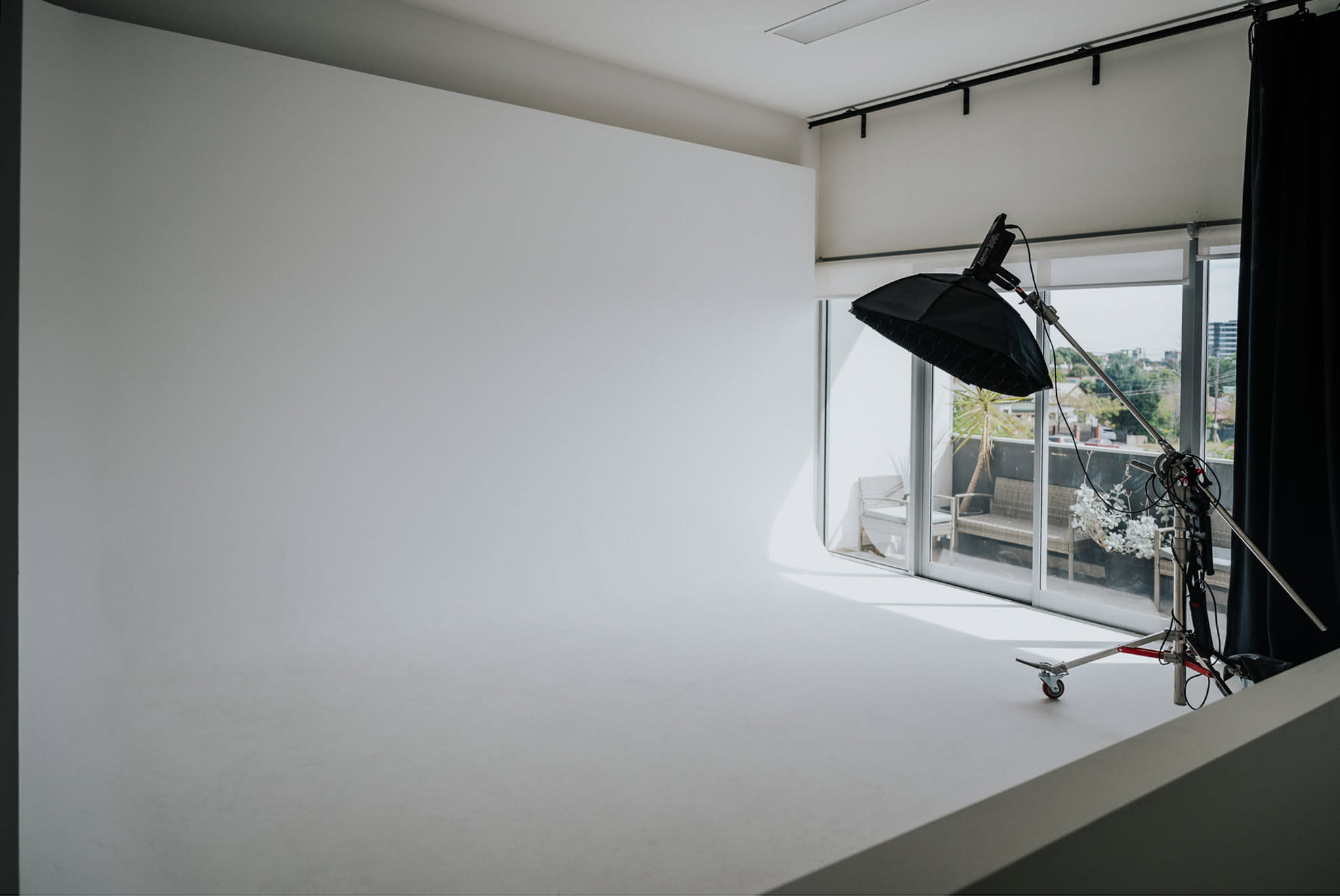 A photographer captures a model posing on the floor during a studio photo shoot with reflective materials and lighting setups.