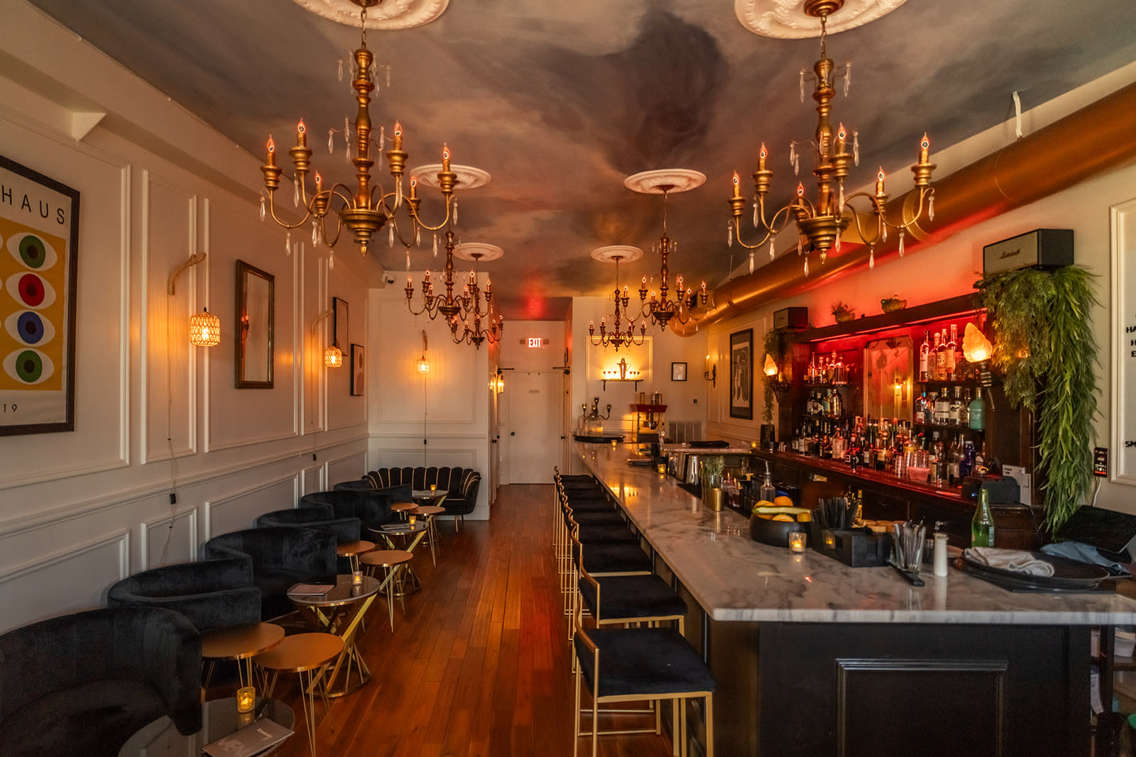 A birthday cake sits on a marble bar surrounded by festive decor and patrons enjoying the celebration.