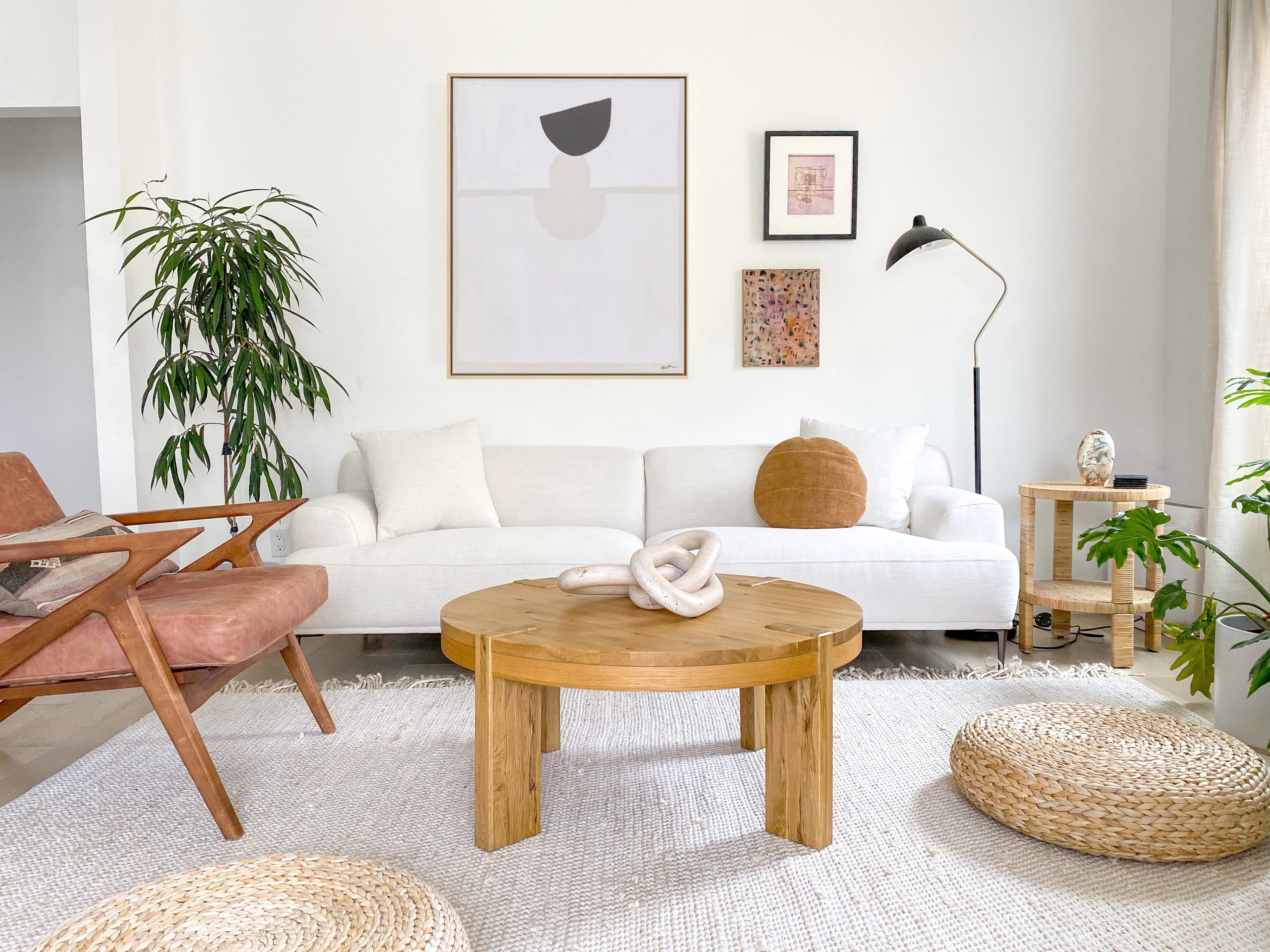 A photoshoot is taking place in a bright, modern living room featuring a couch, coffee table, and a Hollywood sign prominently displayed in the background.
