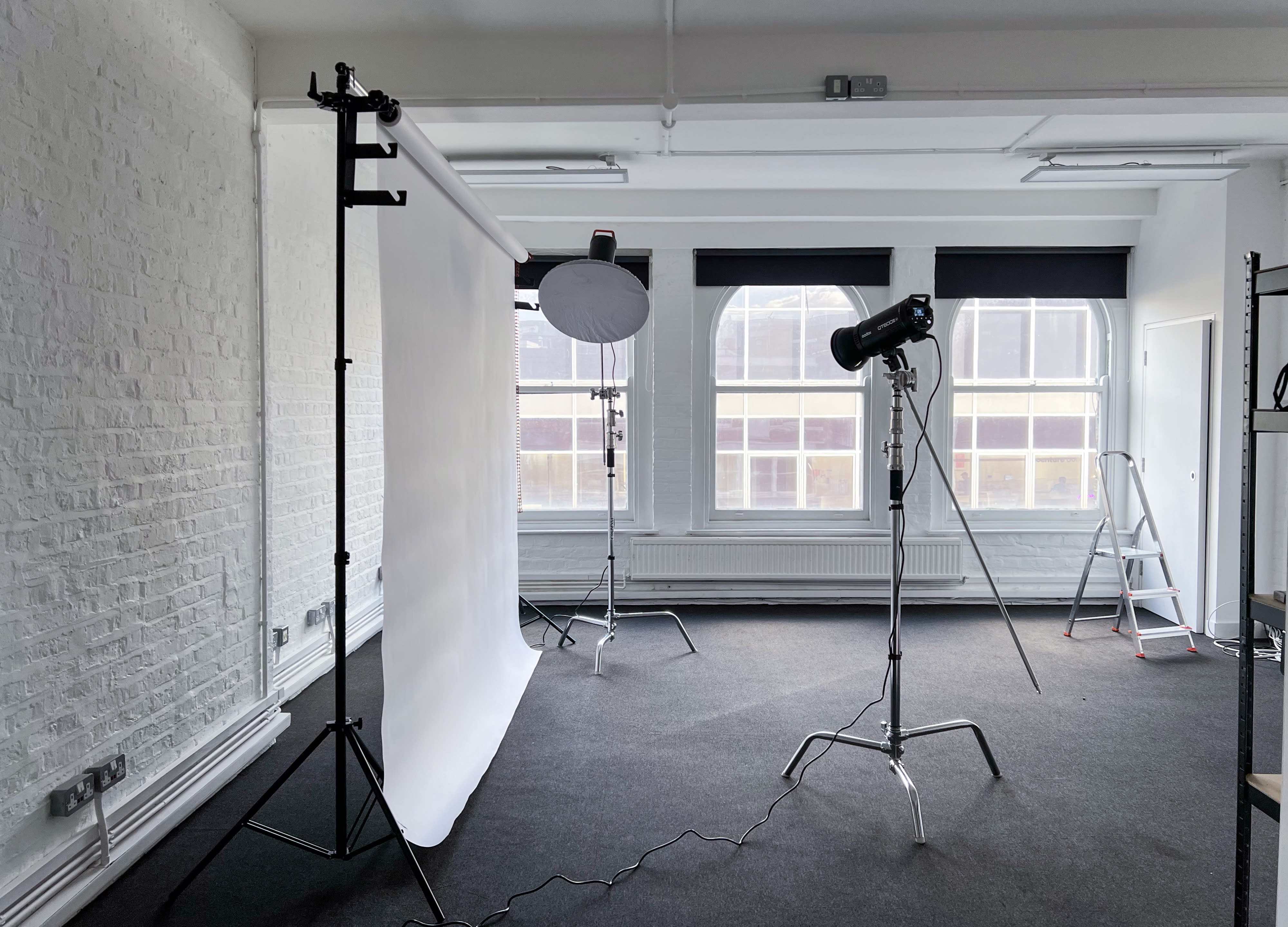 A model stands in a studio against a white backdrop during a photo shoot.