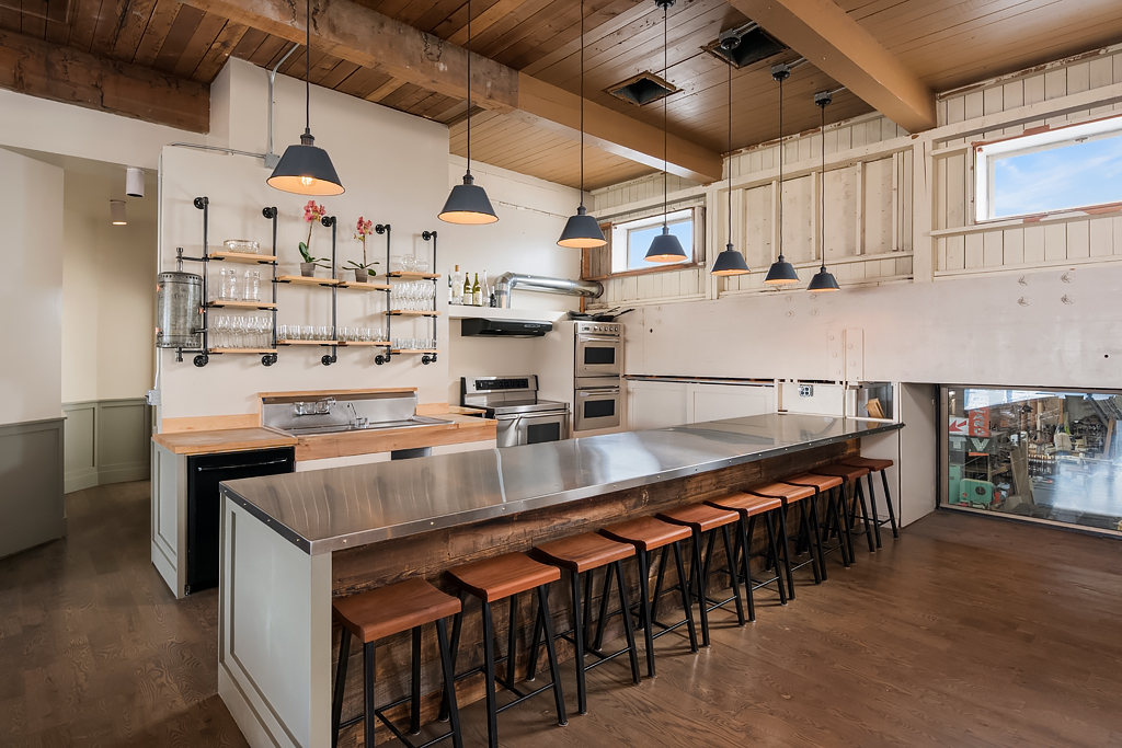 A photographer captures a scene in a cafe featuring barista activity and a set of stools arranged near the bar.
