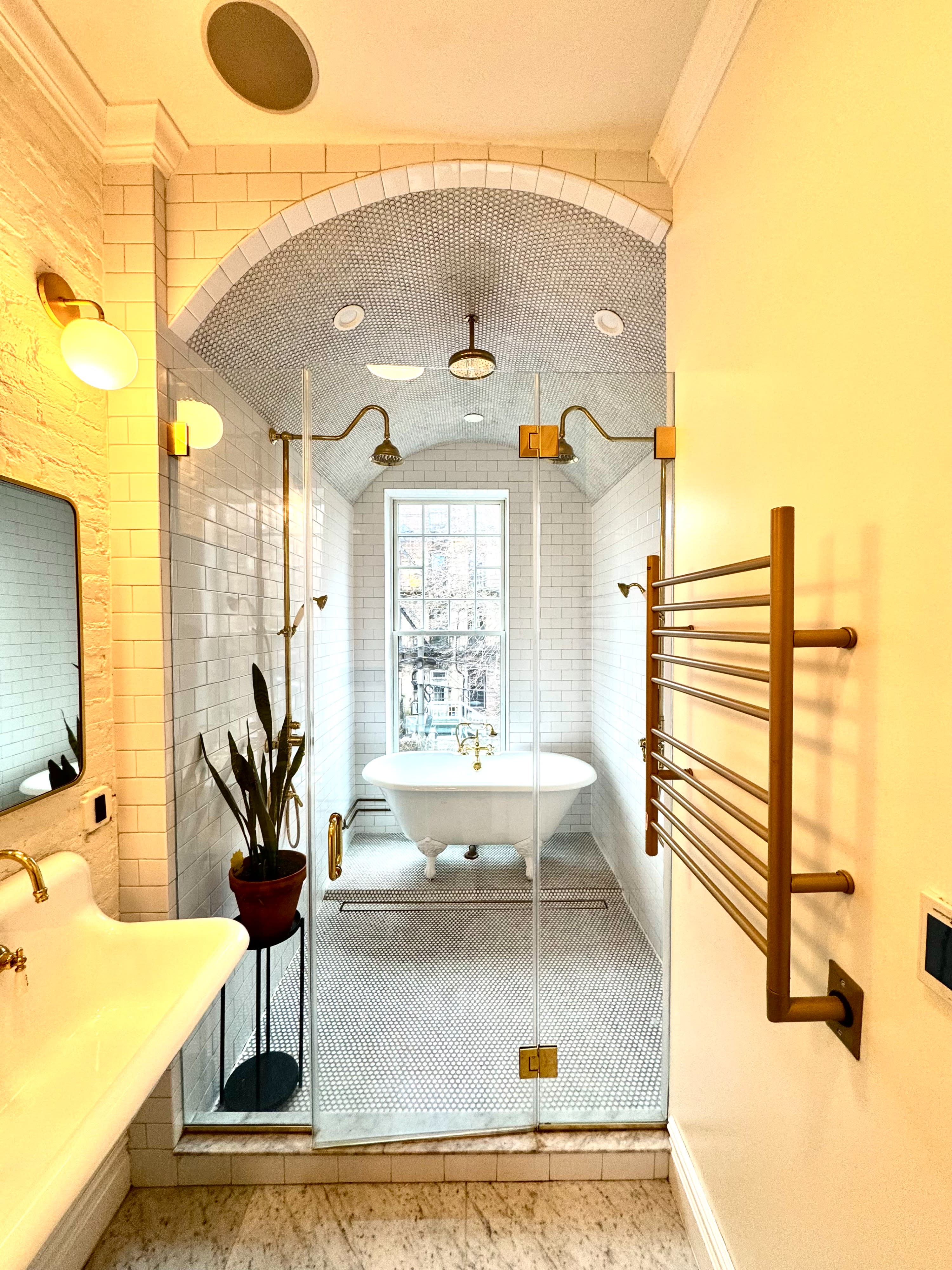 A video shoot is taking place in a bright, modern bathroom featuring a freestanding bathtub and a large window.