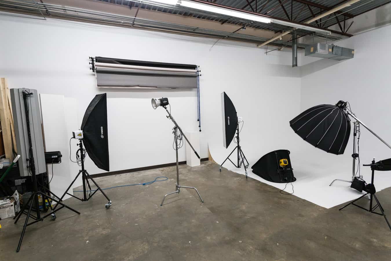 A person poses on one leg beside a white pedestal in a photography studio.