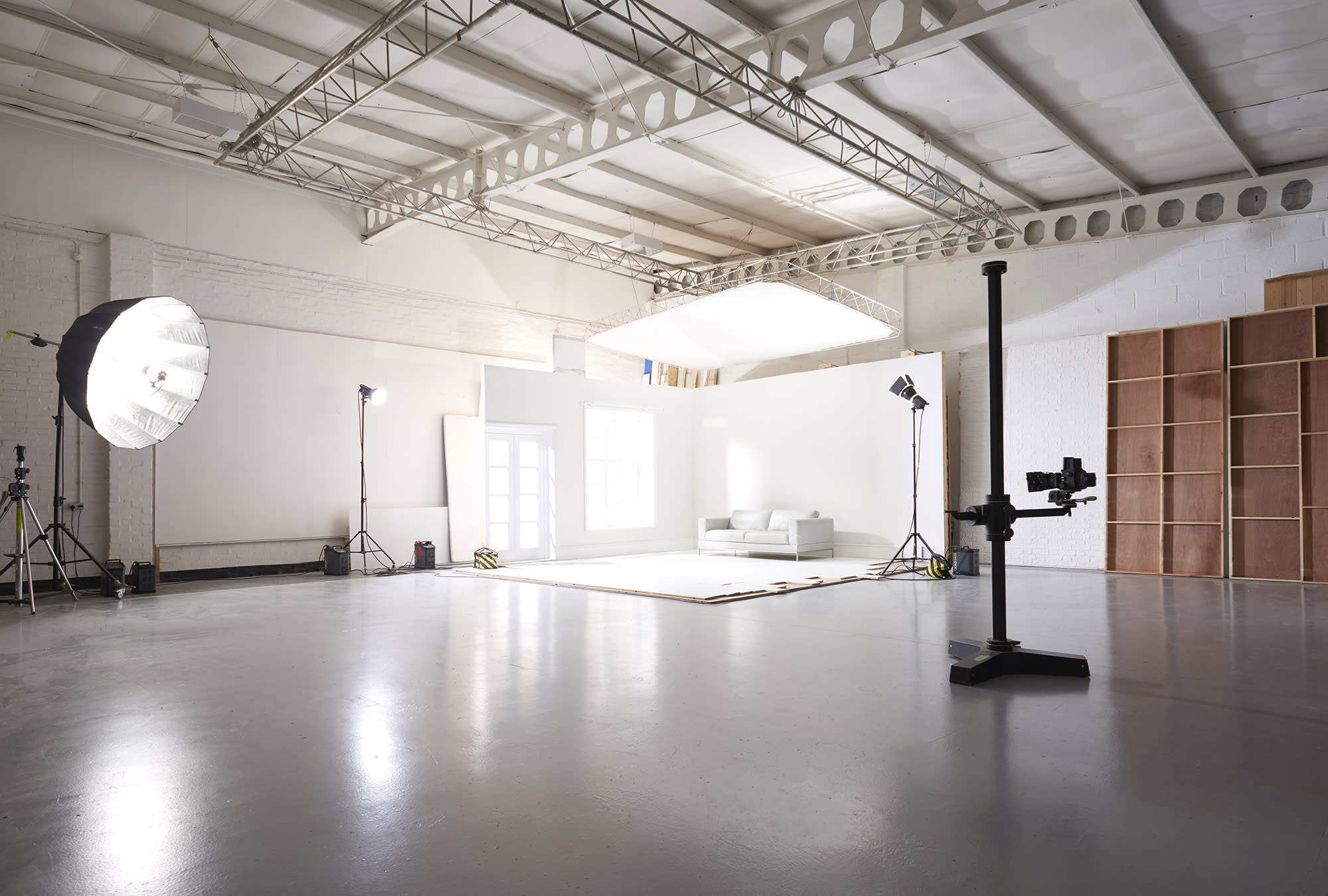 A photographer captures an image of a model posing on a white backdrop in a studio.