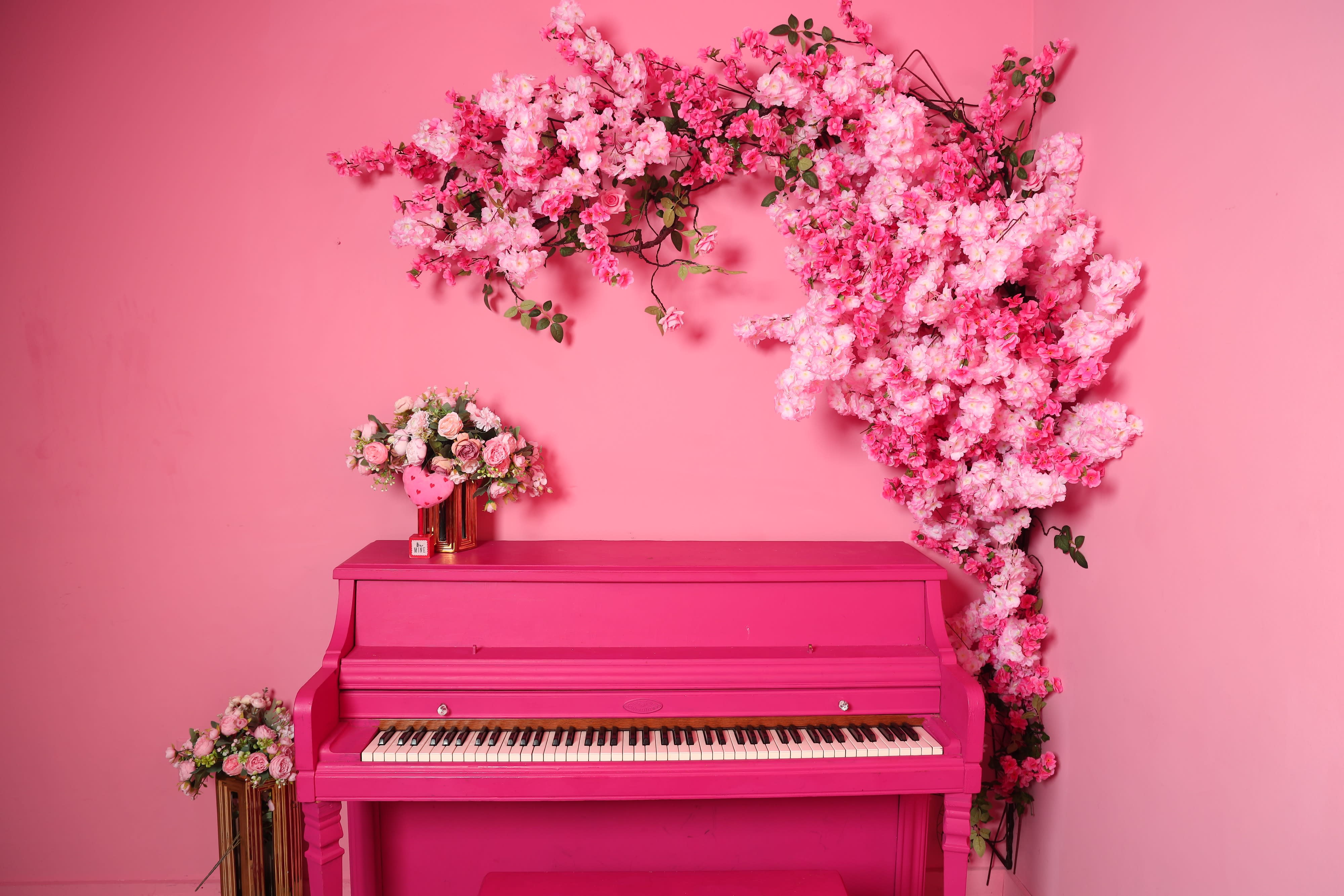 A young girl in a pink dress sits on a golden-framed couch in a brightly colored pink photo shoot setting.
