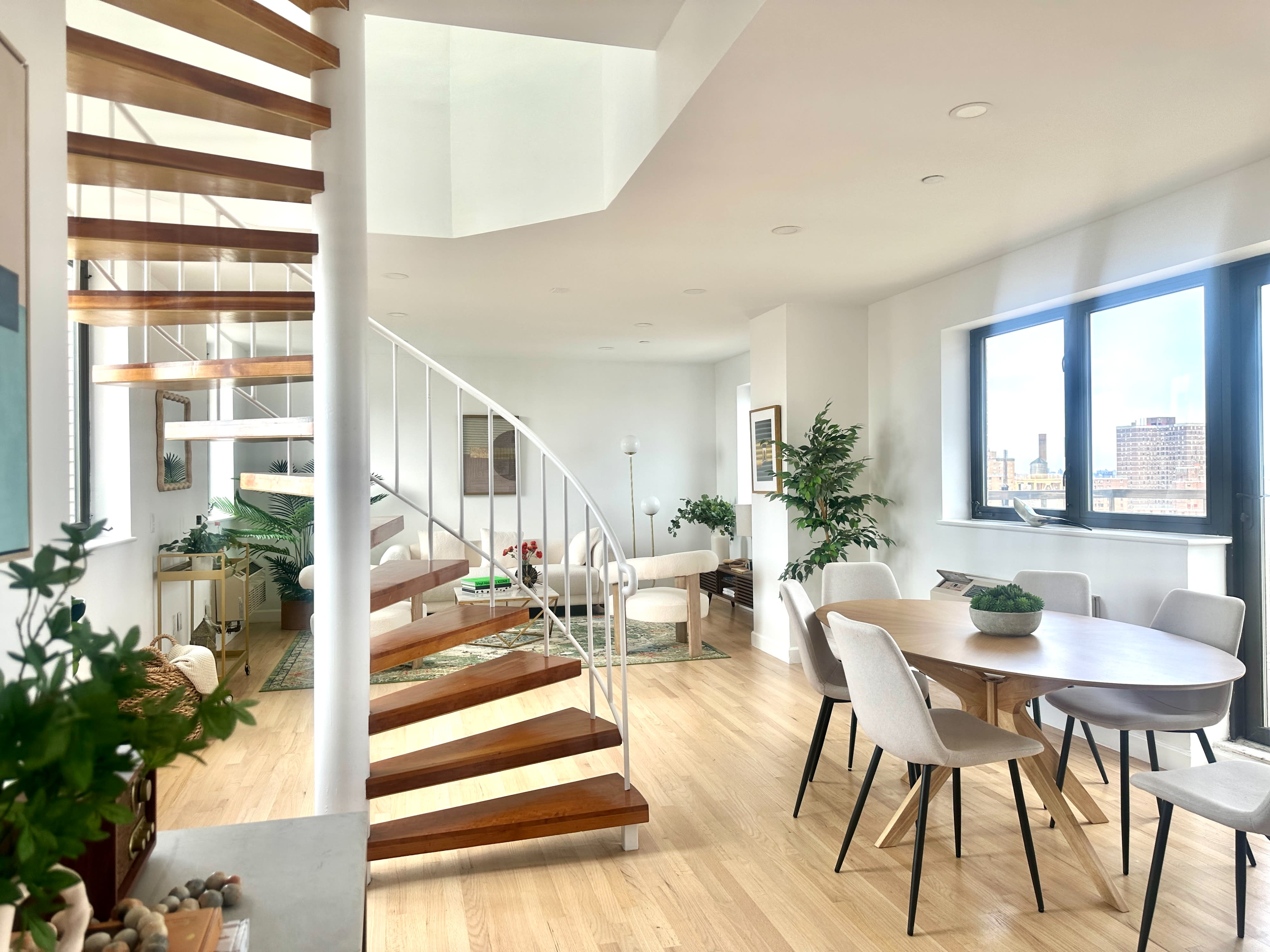 A photo shoot captures a modern interior featuring a spiral staircase, a cozy living area, and a dining space with stylish furniture.