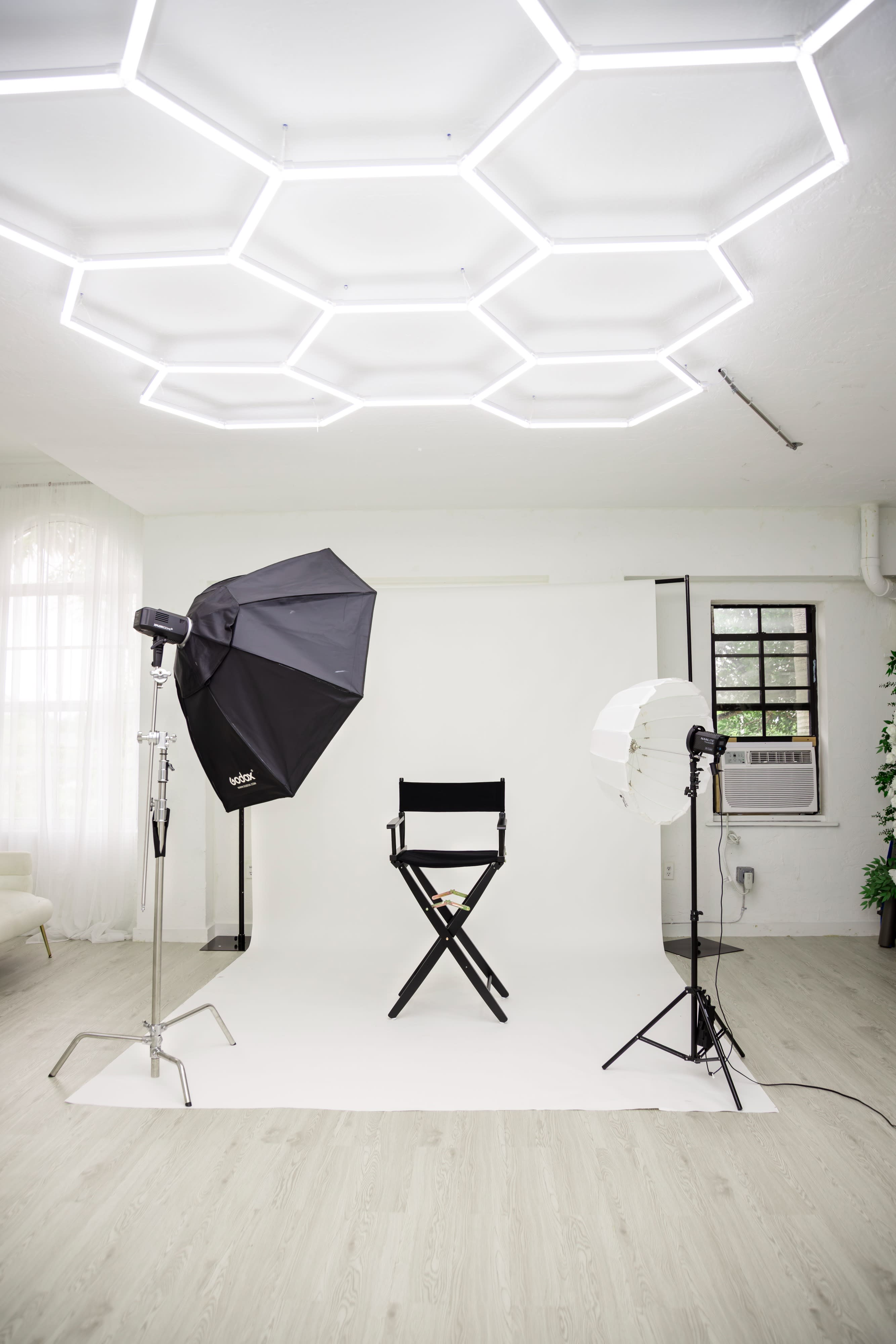 A well-lit studio features a stylish sofa, large mirror, and a teddy bear, set up for a brand photoshoot.