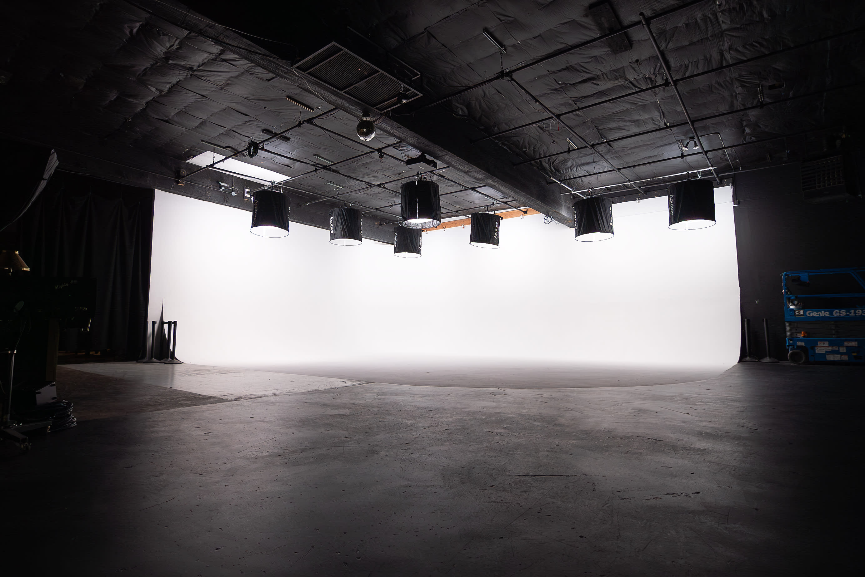 Two performers are striking dynamic poses in a brightly lit studio during a video shoot.