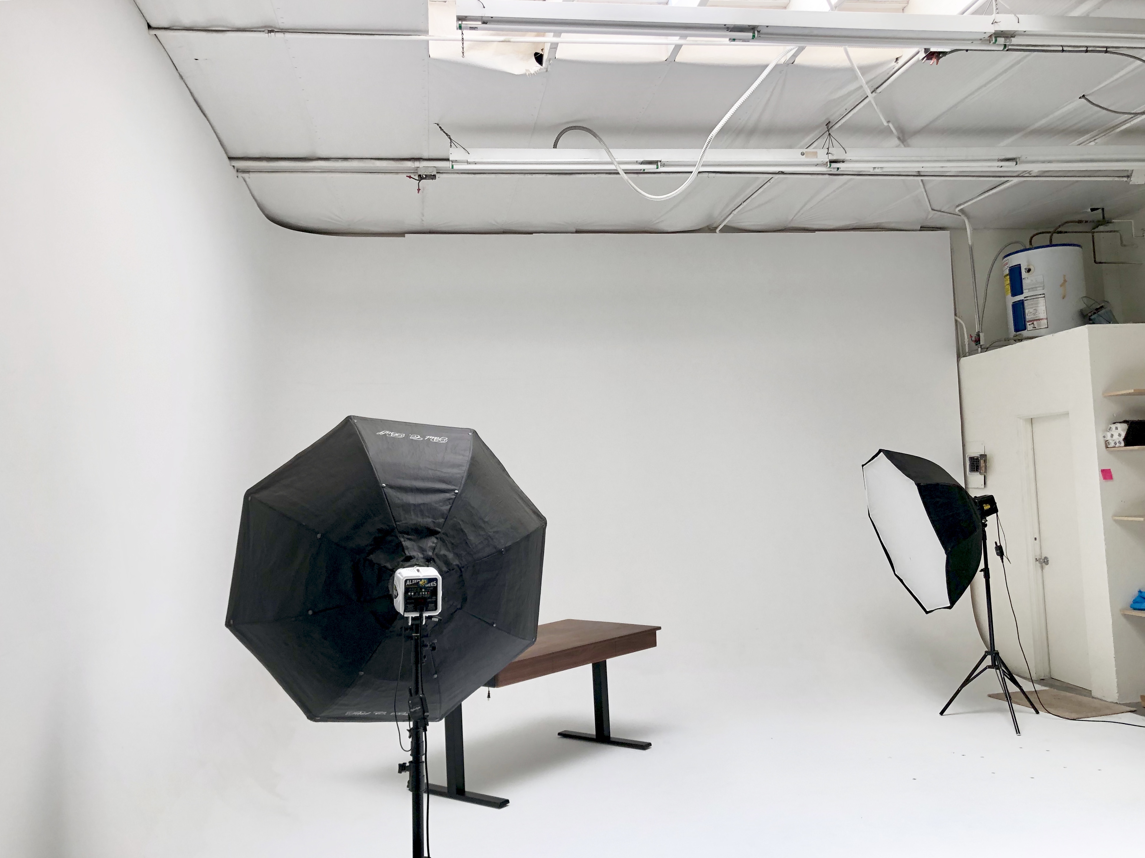A film shoot setup for an interview features a camera on a track, a neatly positioned chair, and lighting equipment in a white studio.