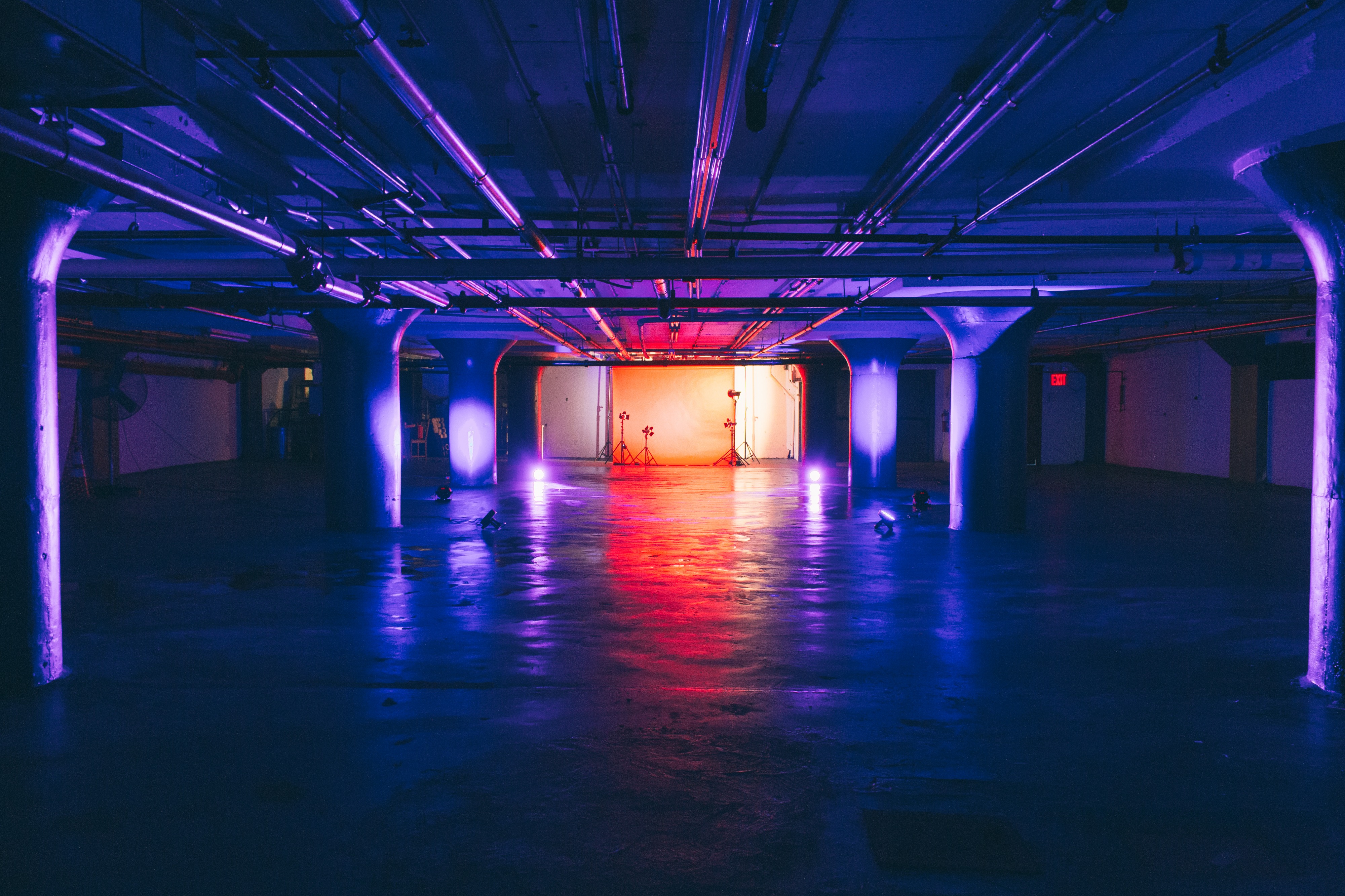 A videographer captures a scene featuring two models in a parking garage, with one wearing stylish high heels and the other in casual attire.