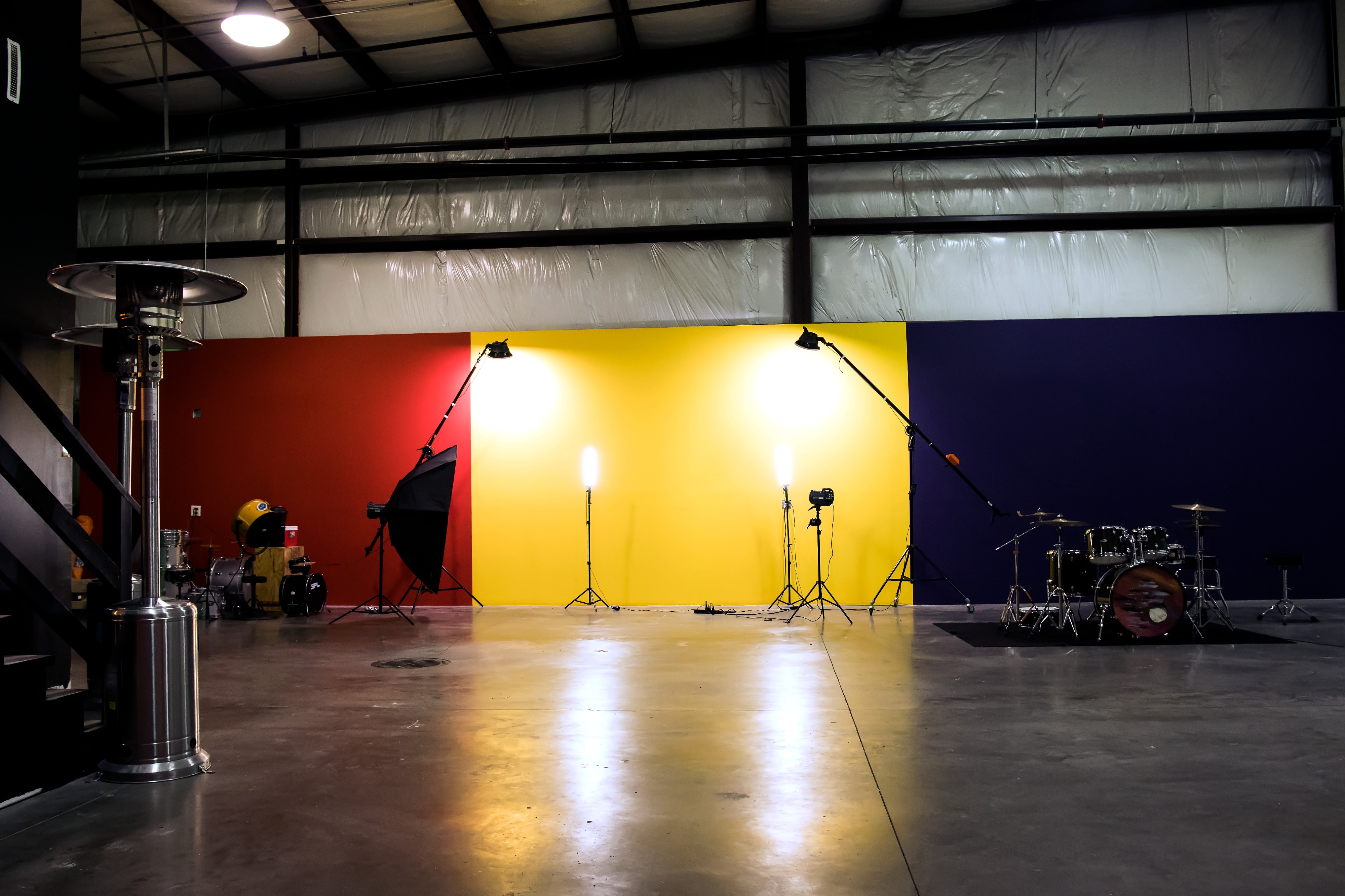 A group of people sits on an orange couch while others gather in a space with colorful walls and a staircase in the background.