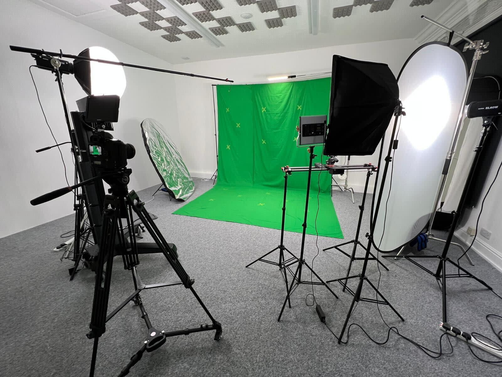 A man stands in front of a bright backdrop while being filmed by multiple cameras during a video shoot.